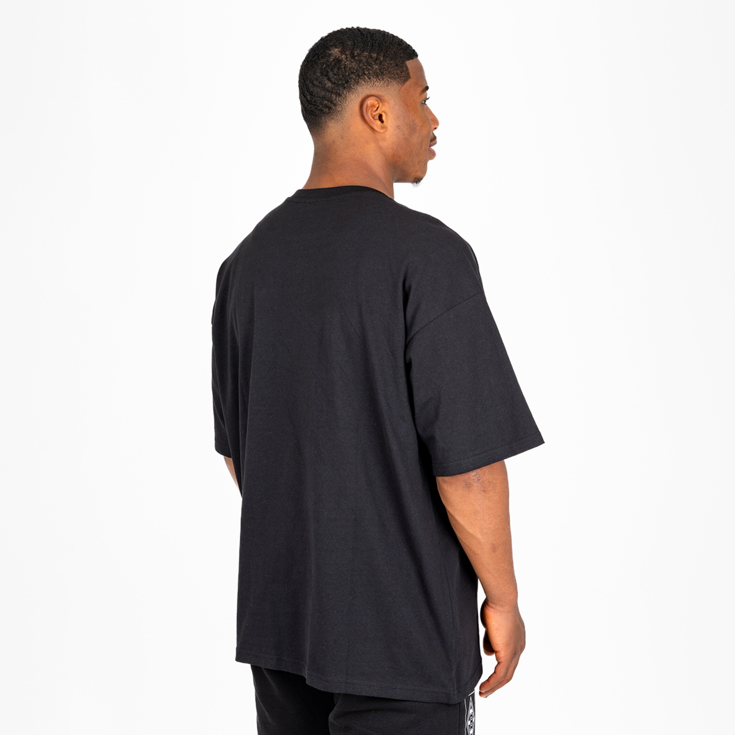 Man viewed from the back wearing a black oversized T-shirt.