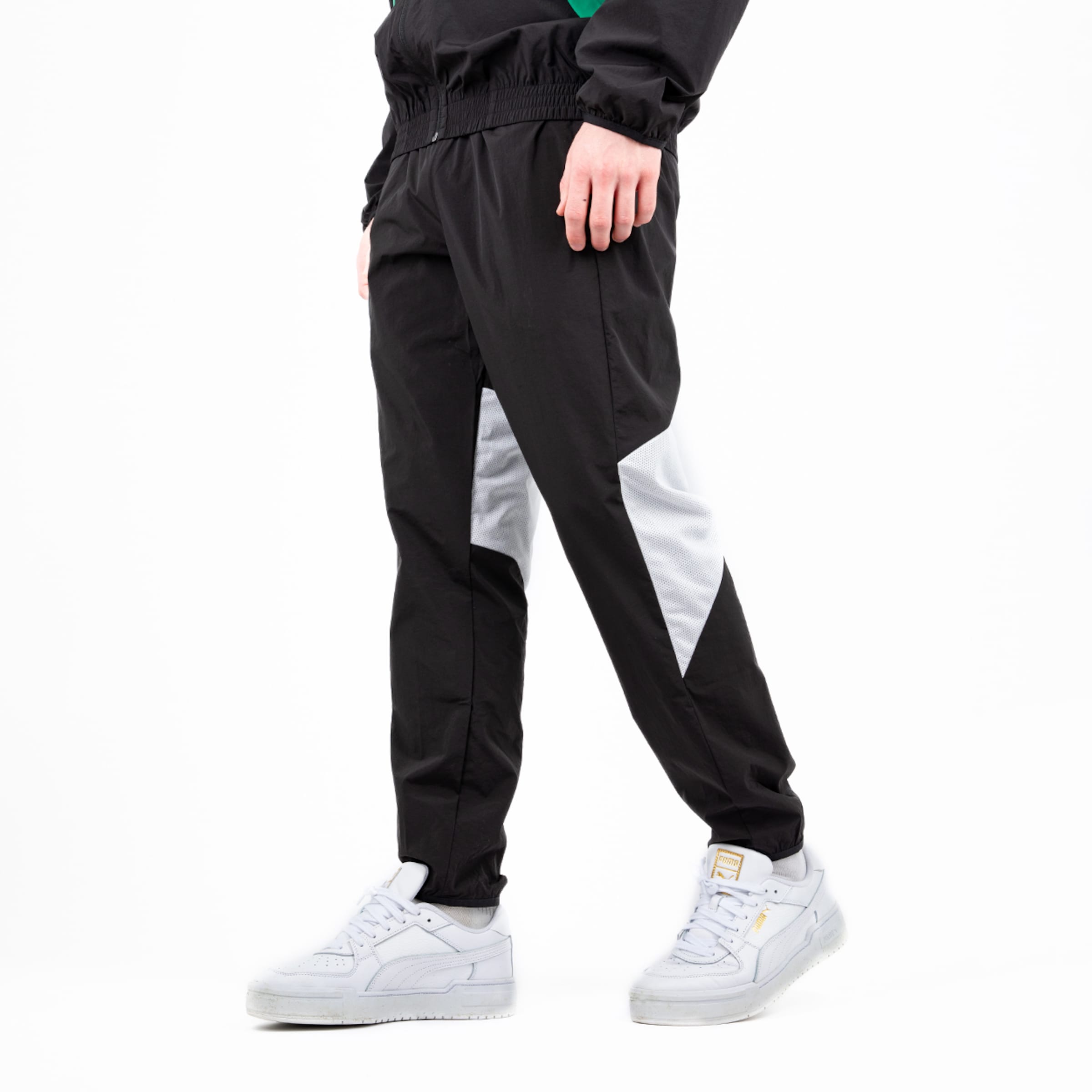 Schwarze Sporthose mit grauen Einsätzen kombiniert mit weißen Sneakers.