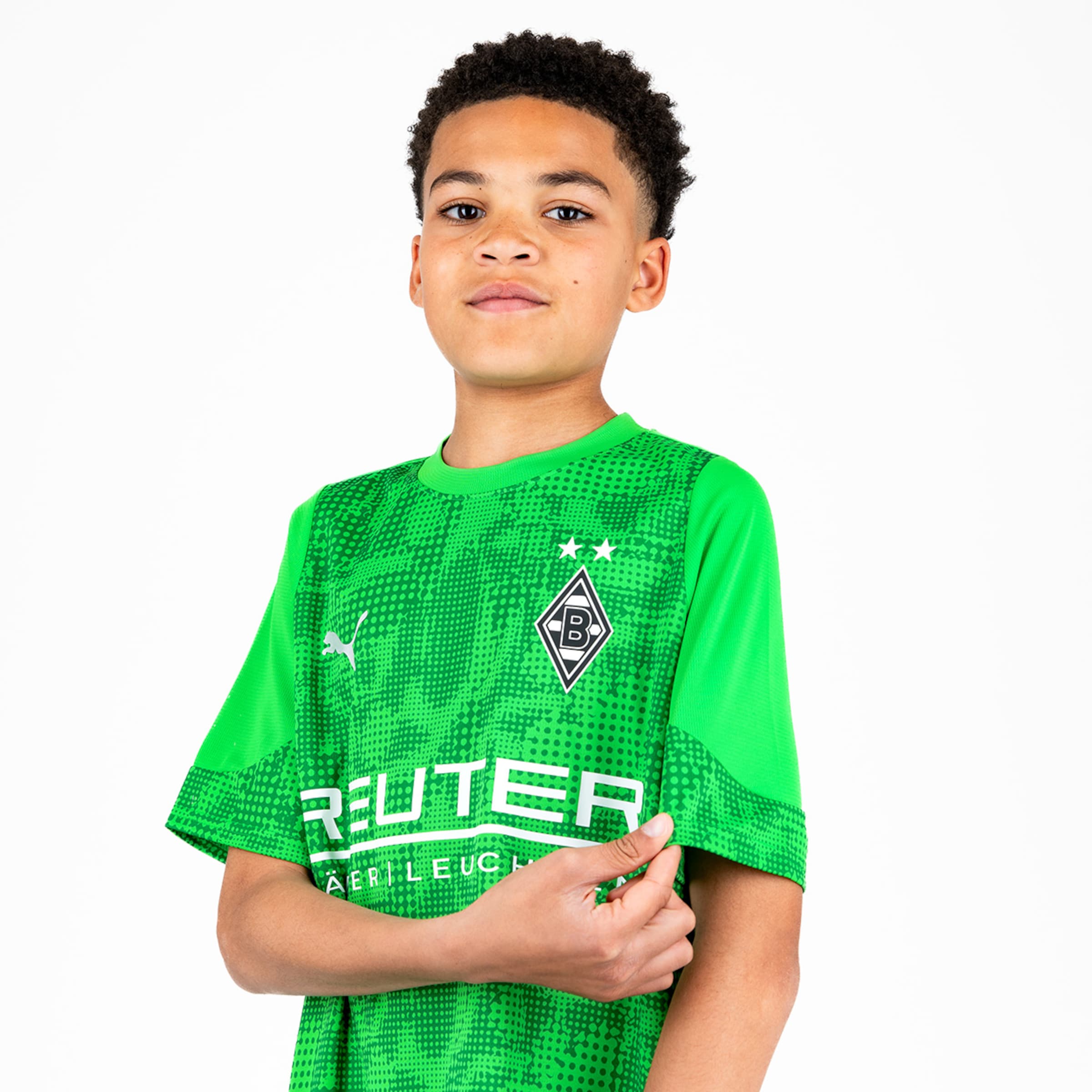 Ein junger Fußballspieler in einem grünen Trikot mit dem Vereinswappen von Borussia Mönchengladbach auf der Brust.