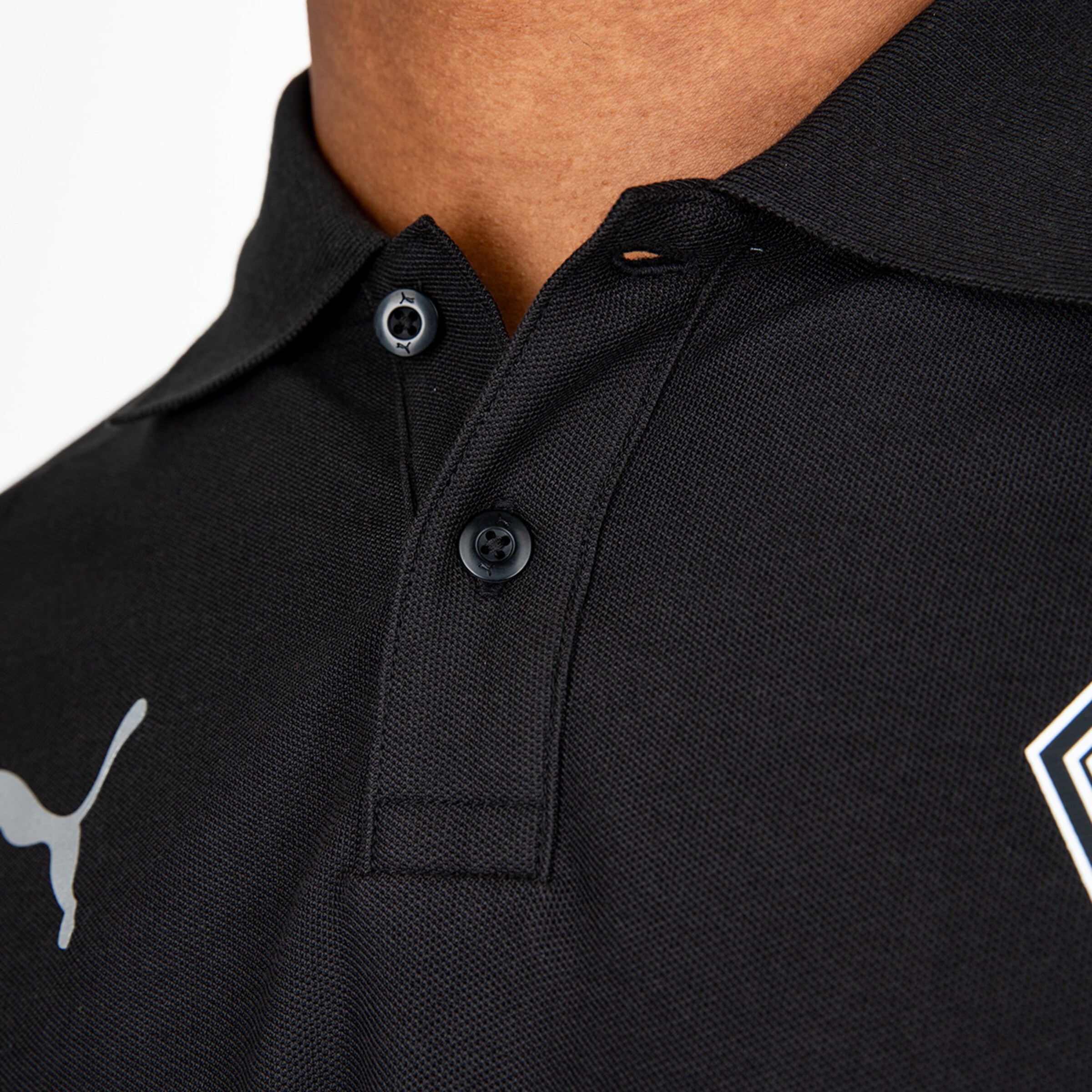 Detailansicht eines schwarzen Poloshirts mit Knöpfen und Puma-Logo.