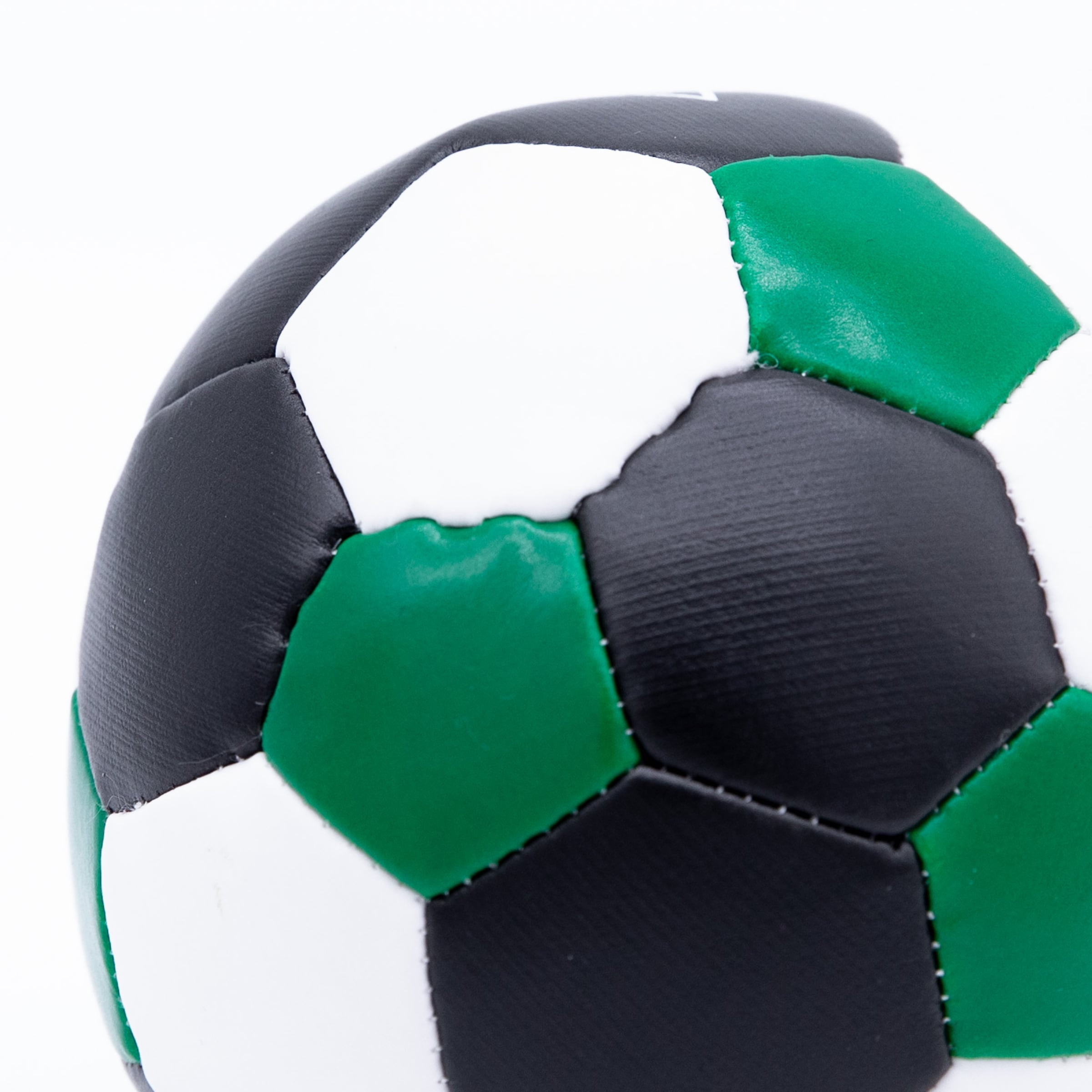 Close-up of a soccer ball with black, white, and green panels and visible stitching.
