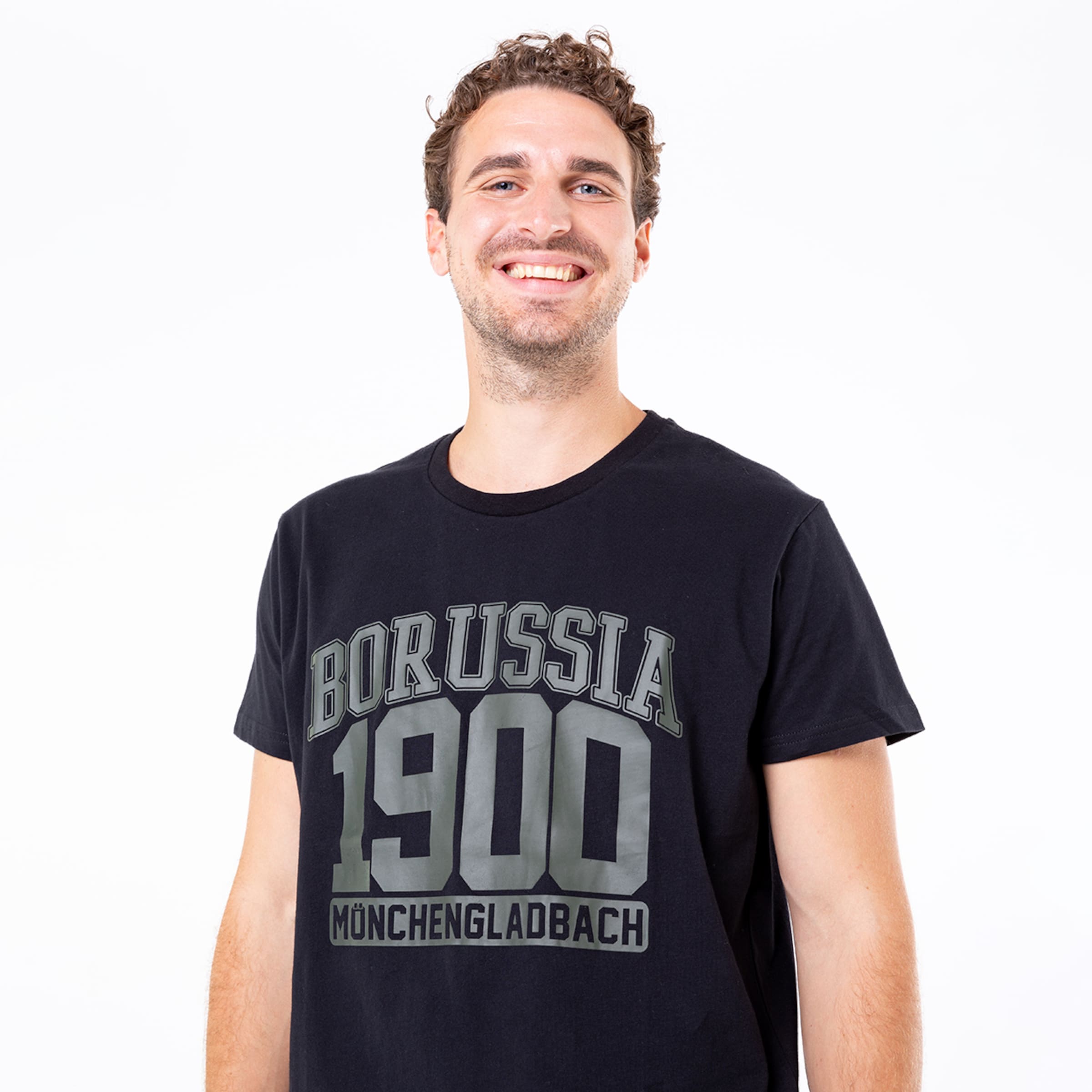 Ein Mann lächelt und trägt ein schwarzes T-Shirt mit dem Aufdruck BORUSSIA 1900 MÖNCHENGLADBACH.