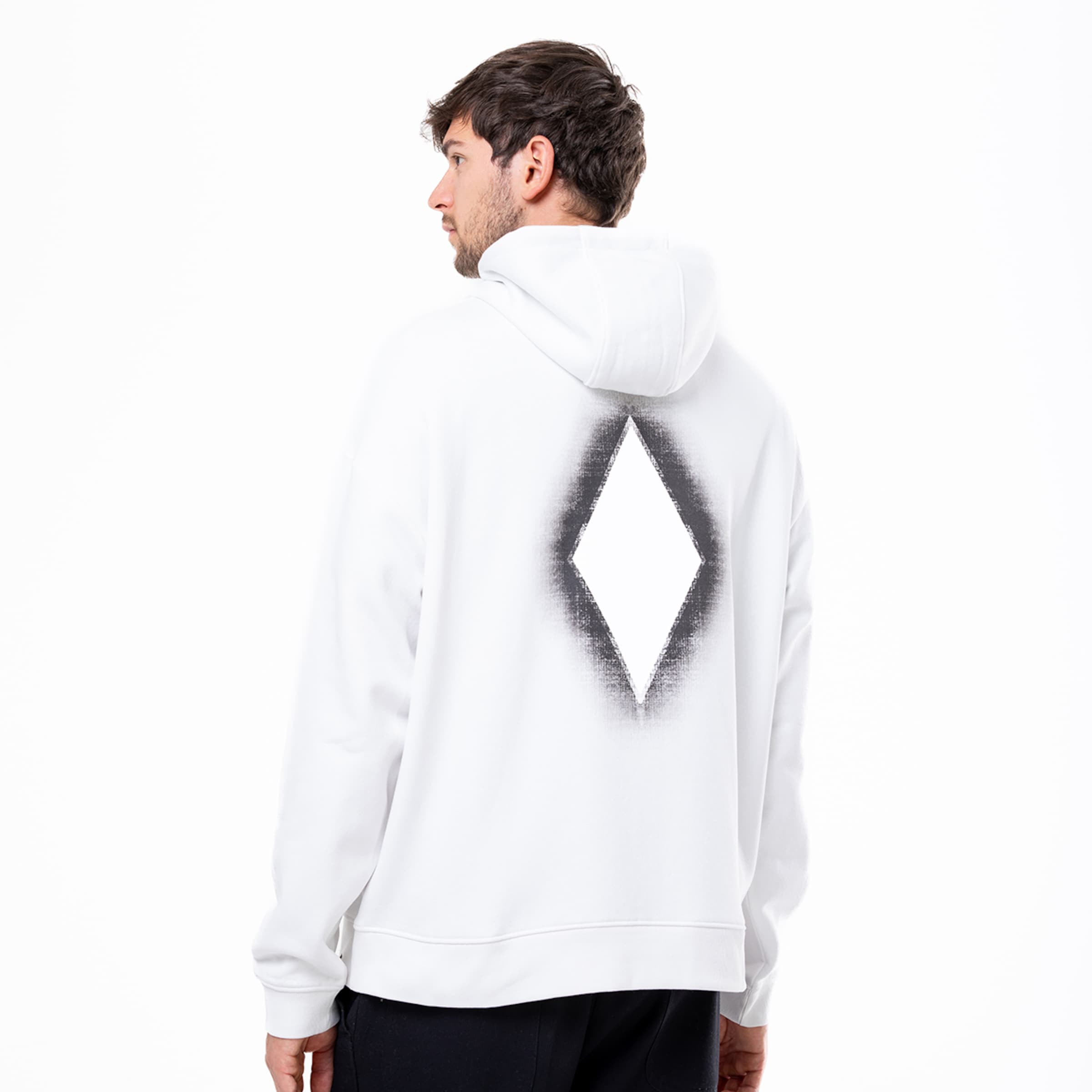 Mann trägt einen weißen Hoodie mit einem schwarzen diamantförmigen Design auf dem Rücken.