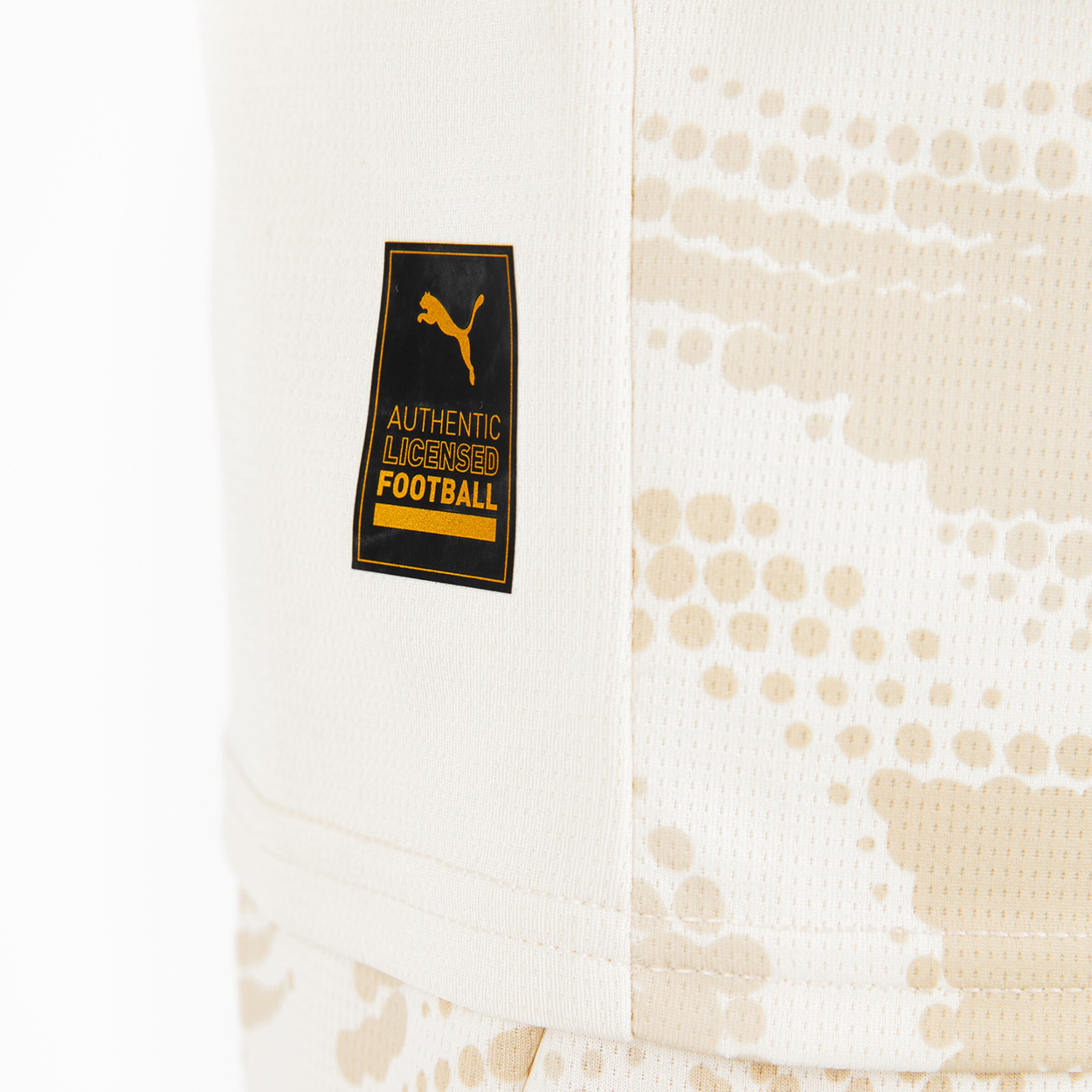 Puma-Logo mit der Aufschrift Authentic Licensed Football auf einem beige-fleckigen Stoff