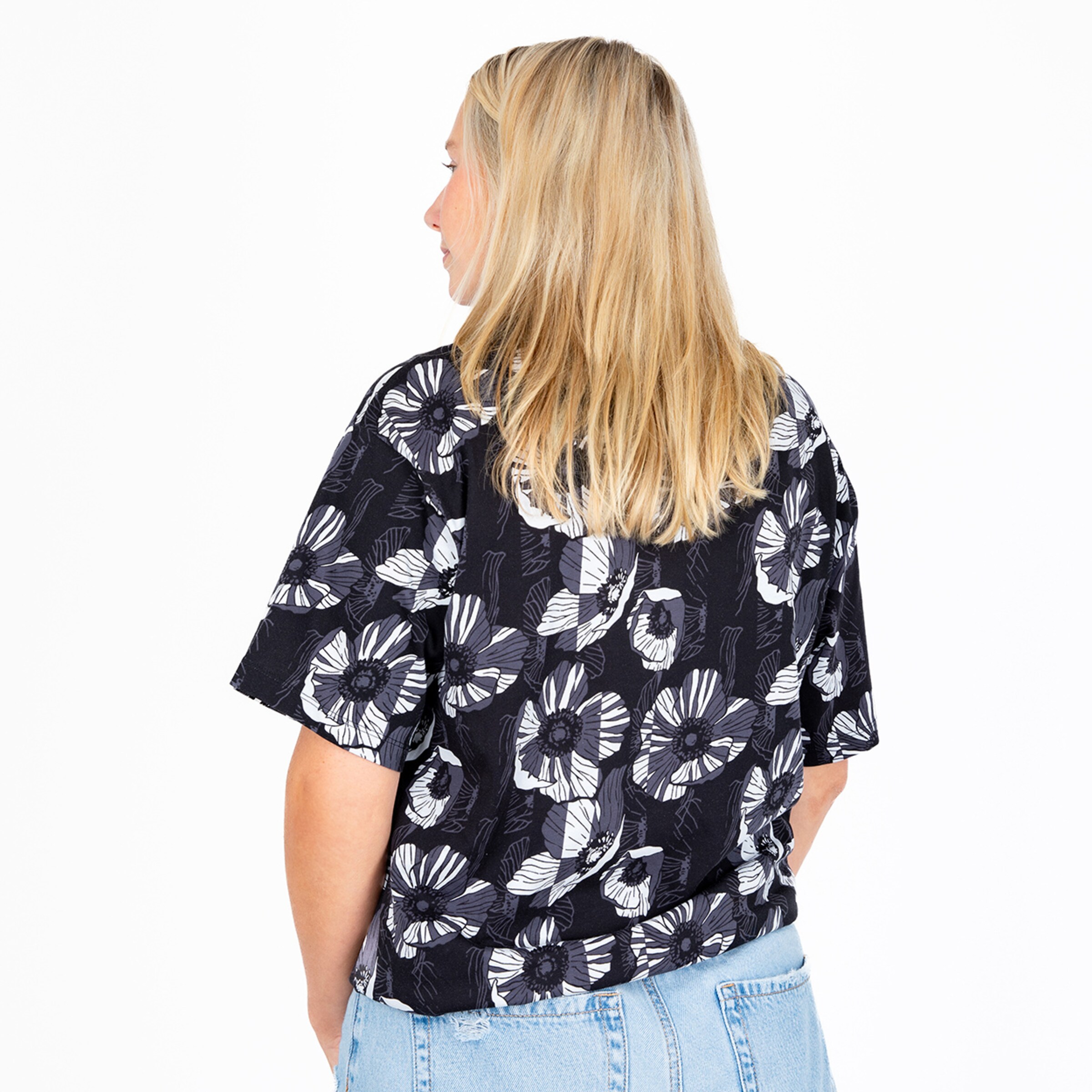 Woman with blonde hair wearing a patterned shirt facing away.