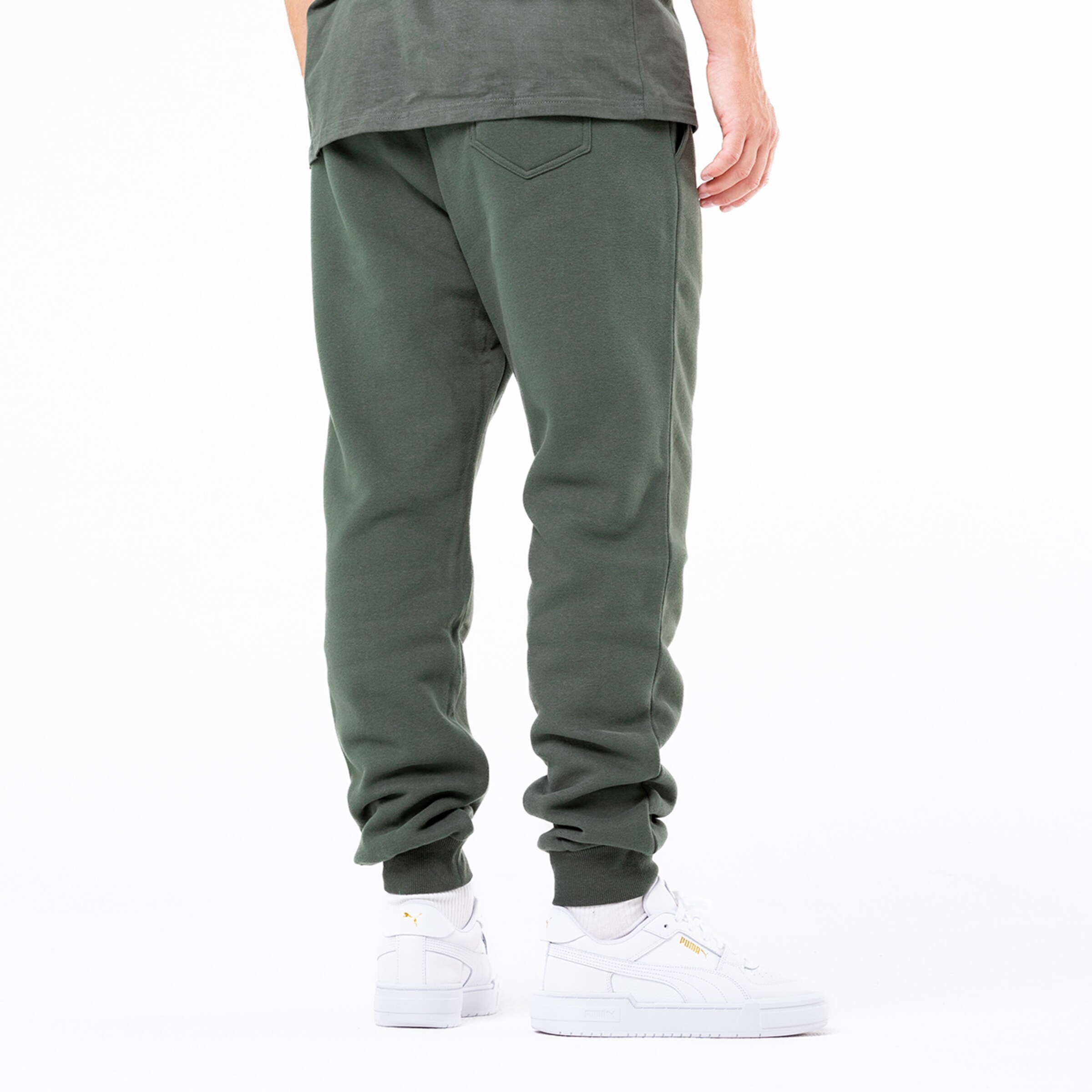 Mann steht mit dem Rücken zu sehen trägt grüne Jogginghosen und weiße Sneakers.