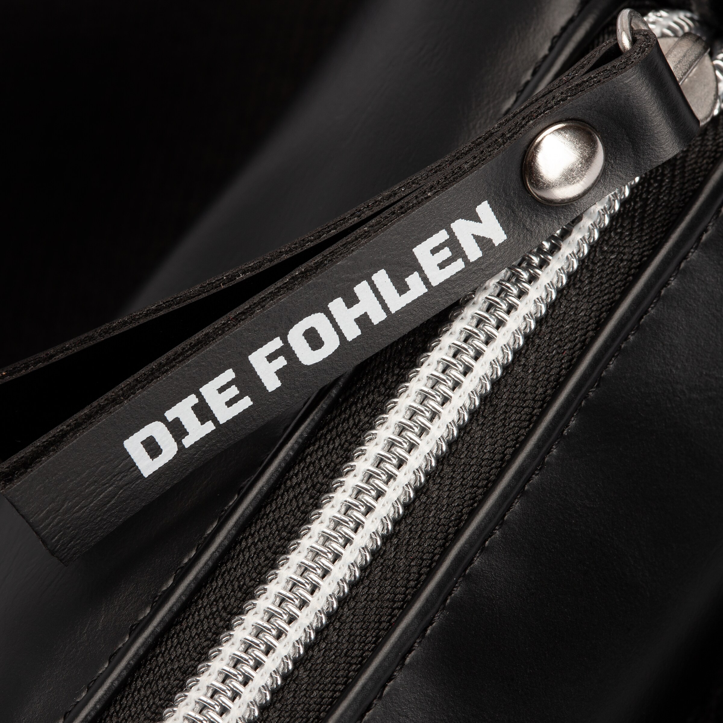 Schwarze Tasche mit Reißverschluss und dem Text DIE FOHLEN.