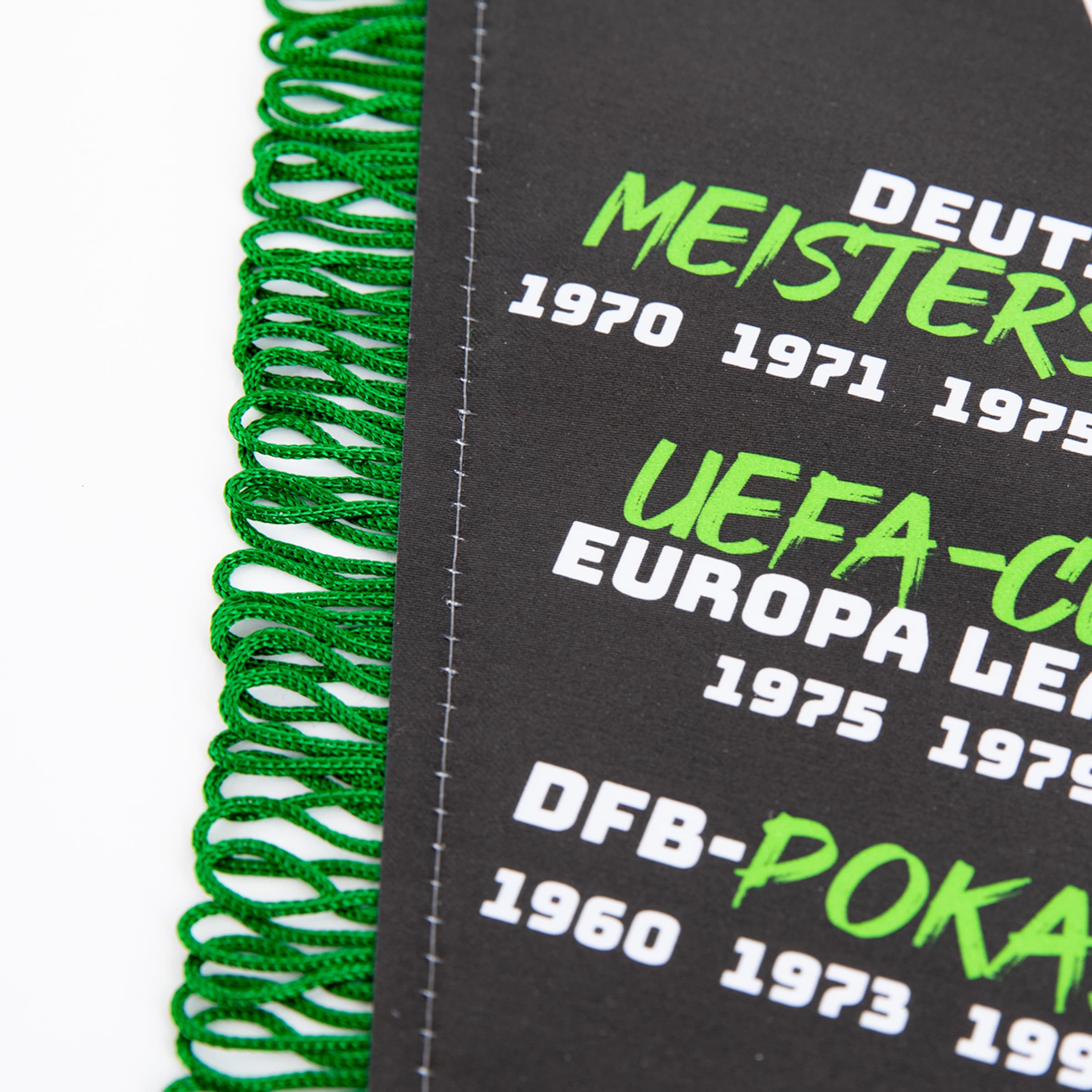Schwarzer Wimpel mit grünen Fransen und Text zu sportlichen Erfolgen (Meisterschaften, UEFA-Cup, DFB-Pokal) sowie Jahreszahlen.