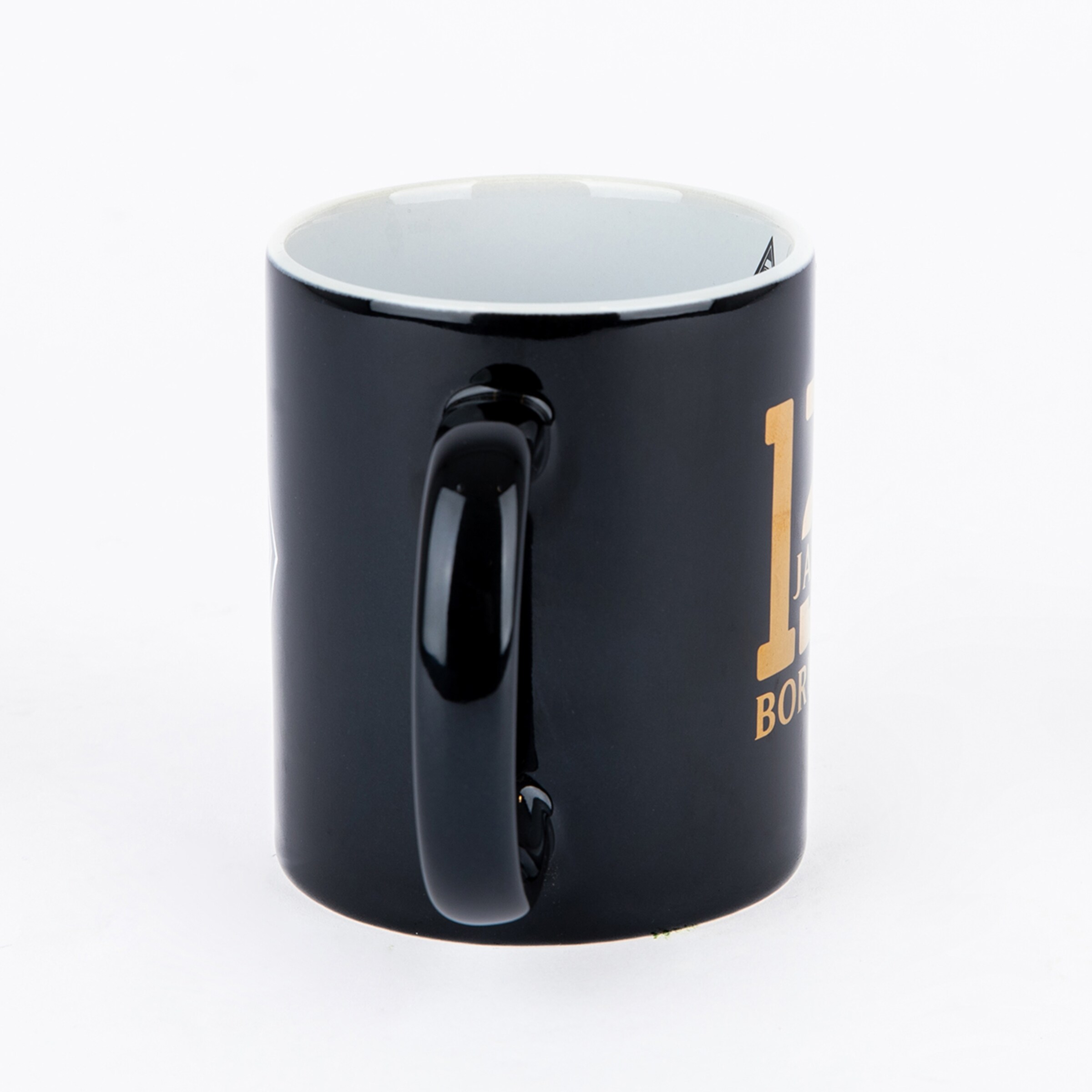 Schwarze Kaffeetasse mit weißer Innenseite und goldenem Aufdruck (Zahl 12 und Wort BOR) vor weißem Hintergrund.
