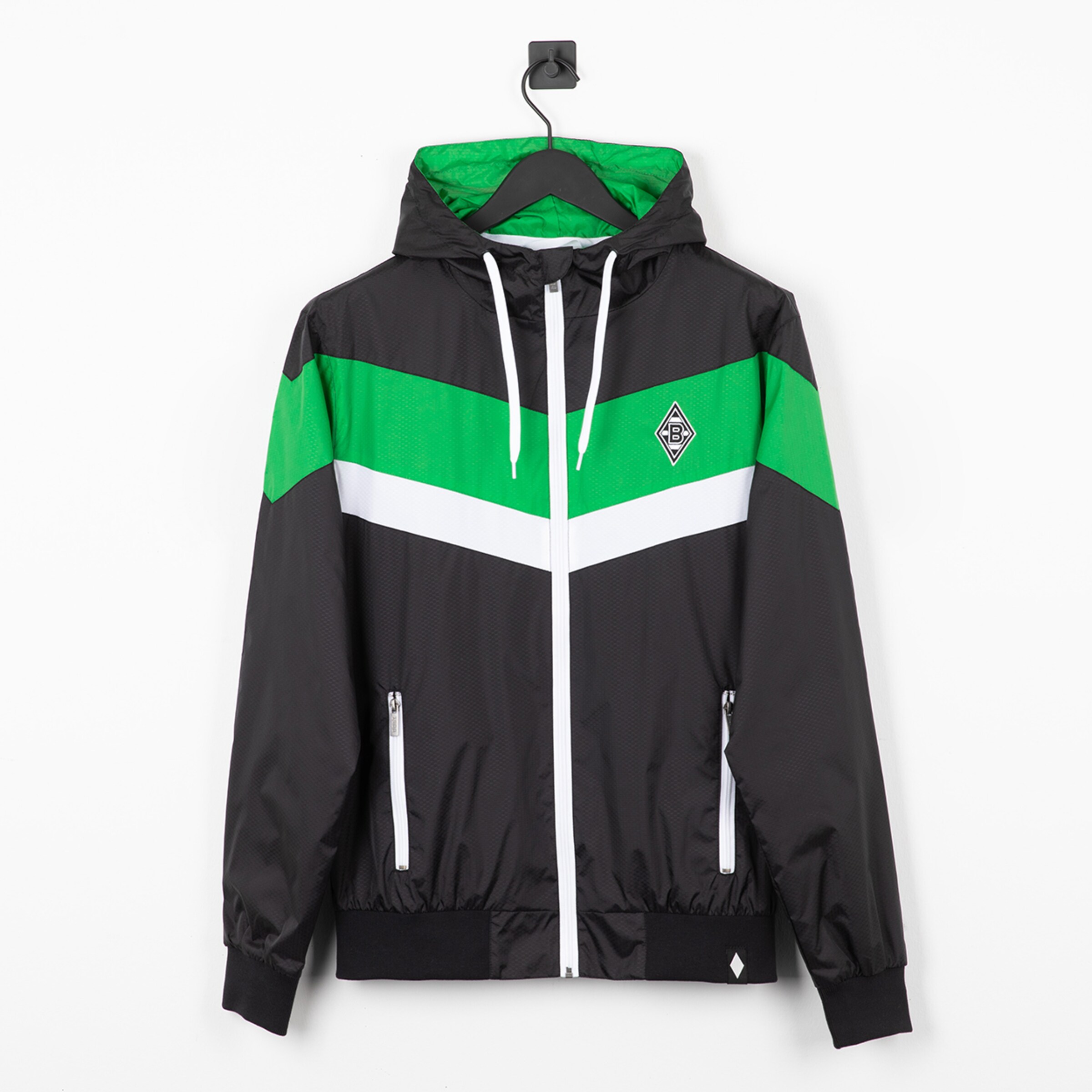 Schwarze Borussia Mönchengladbach Windjacke mit grün-weißen Chevron-Streifen, weißem Reißverschluss und Logo auf der Brust.