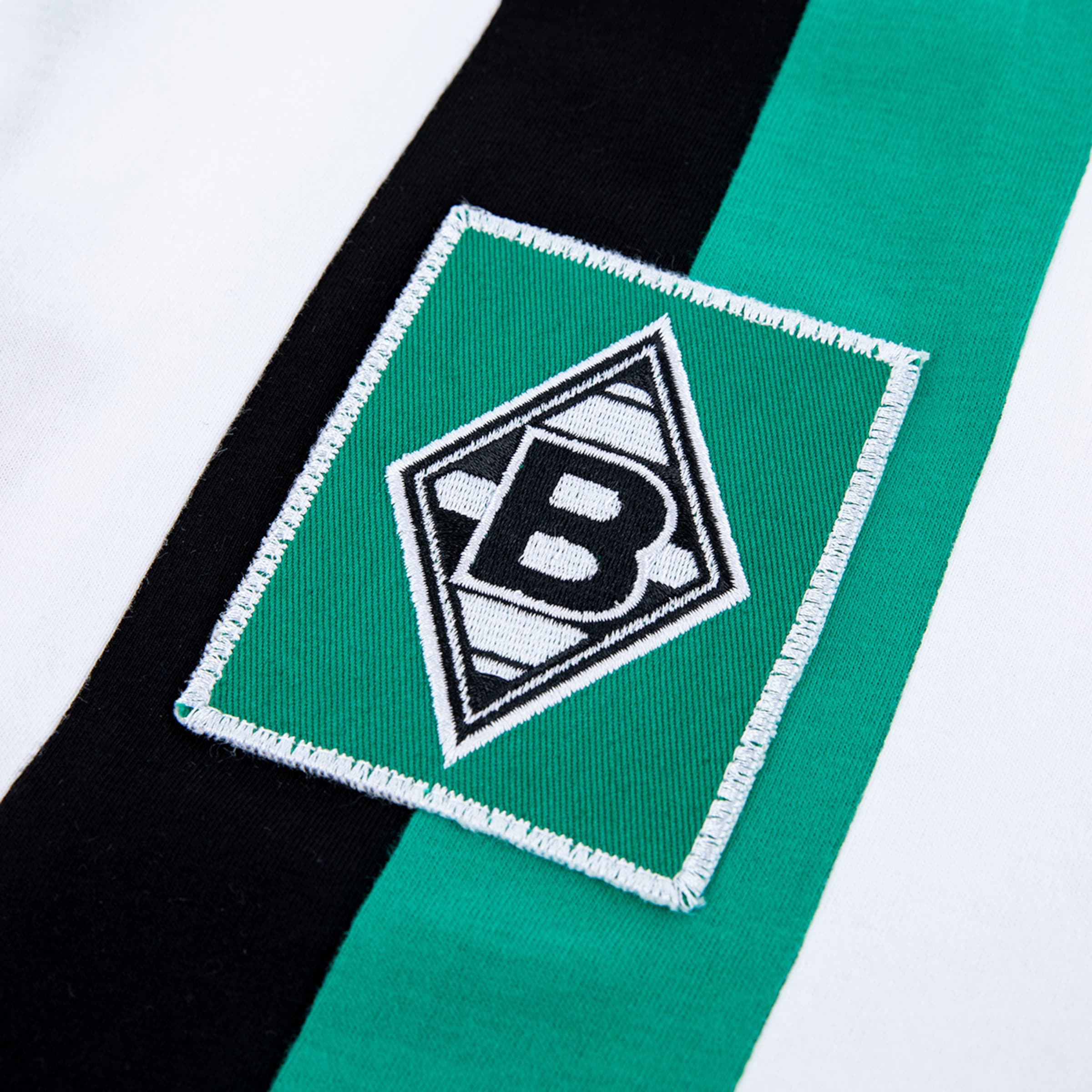 Emblem von Borussia Mönchengladbach auf einem Trikot grün und schwarz gestreift.
