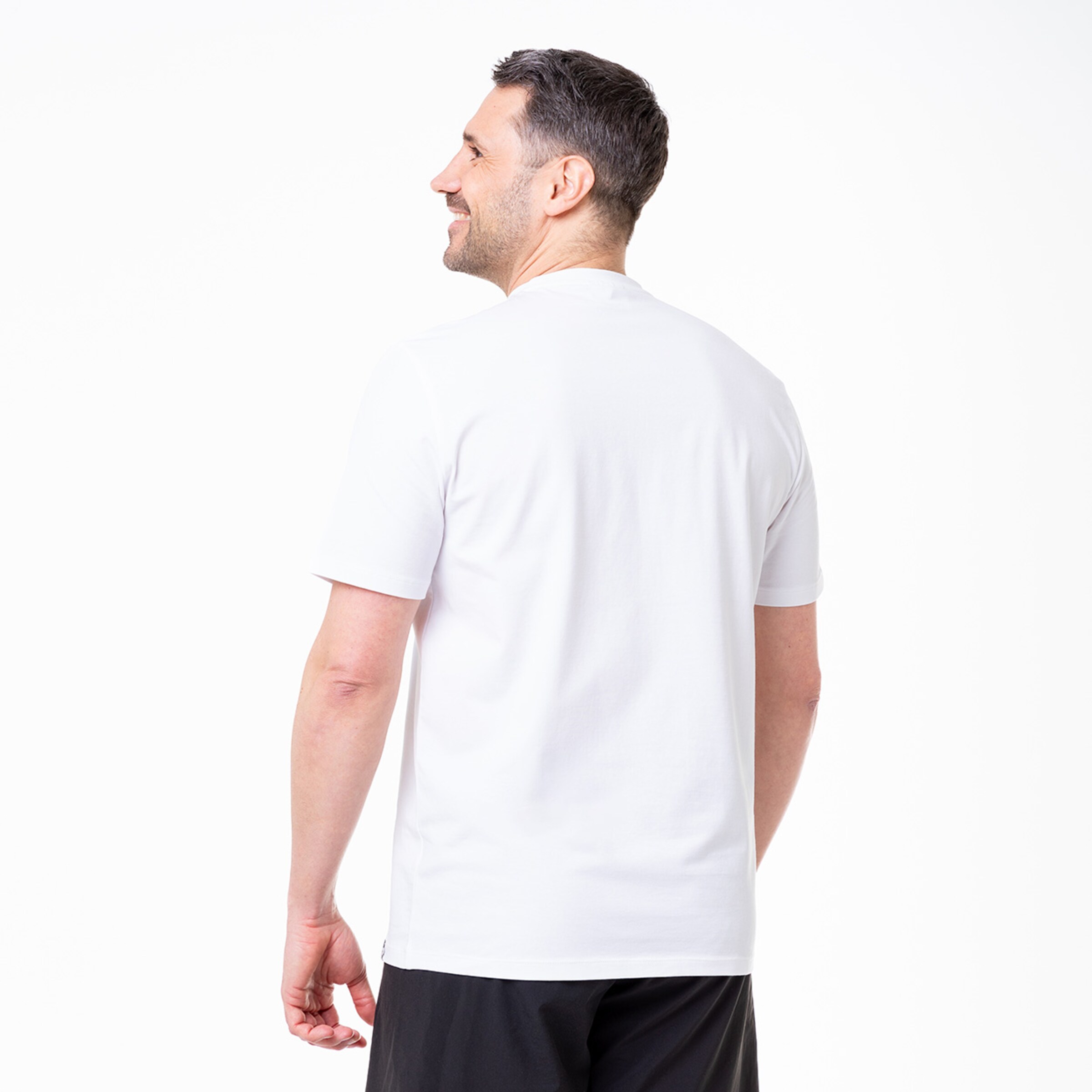 Mann in weißem Sports T-Shirt von hinten lächelnd.