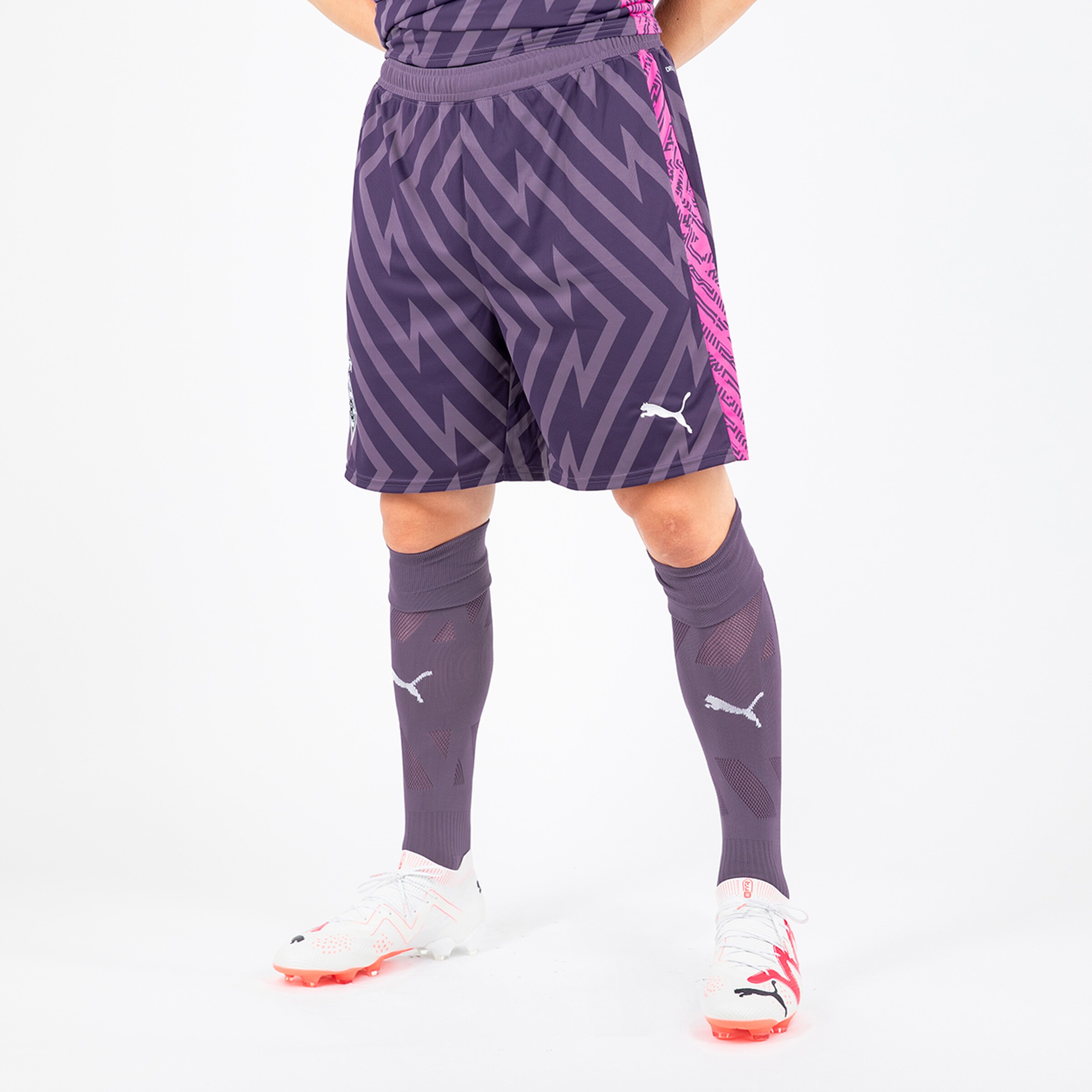 Mann in lila Fußballshorts und Stutzen trägt Schuhmarke Puma