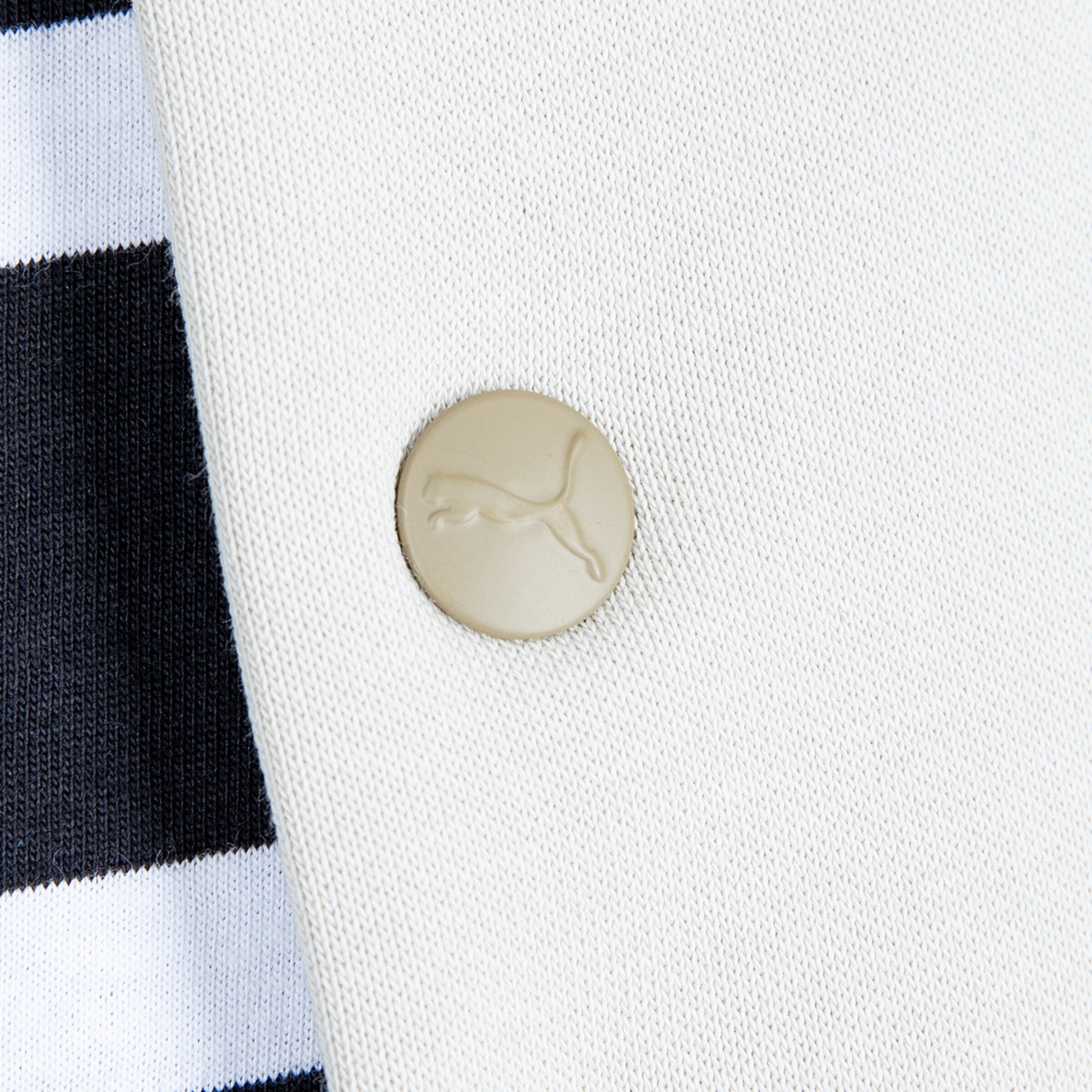 Materialdetail eines Kleidungsstücks mit PUMA-Logo und gestreiftem Design.