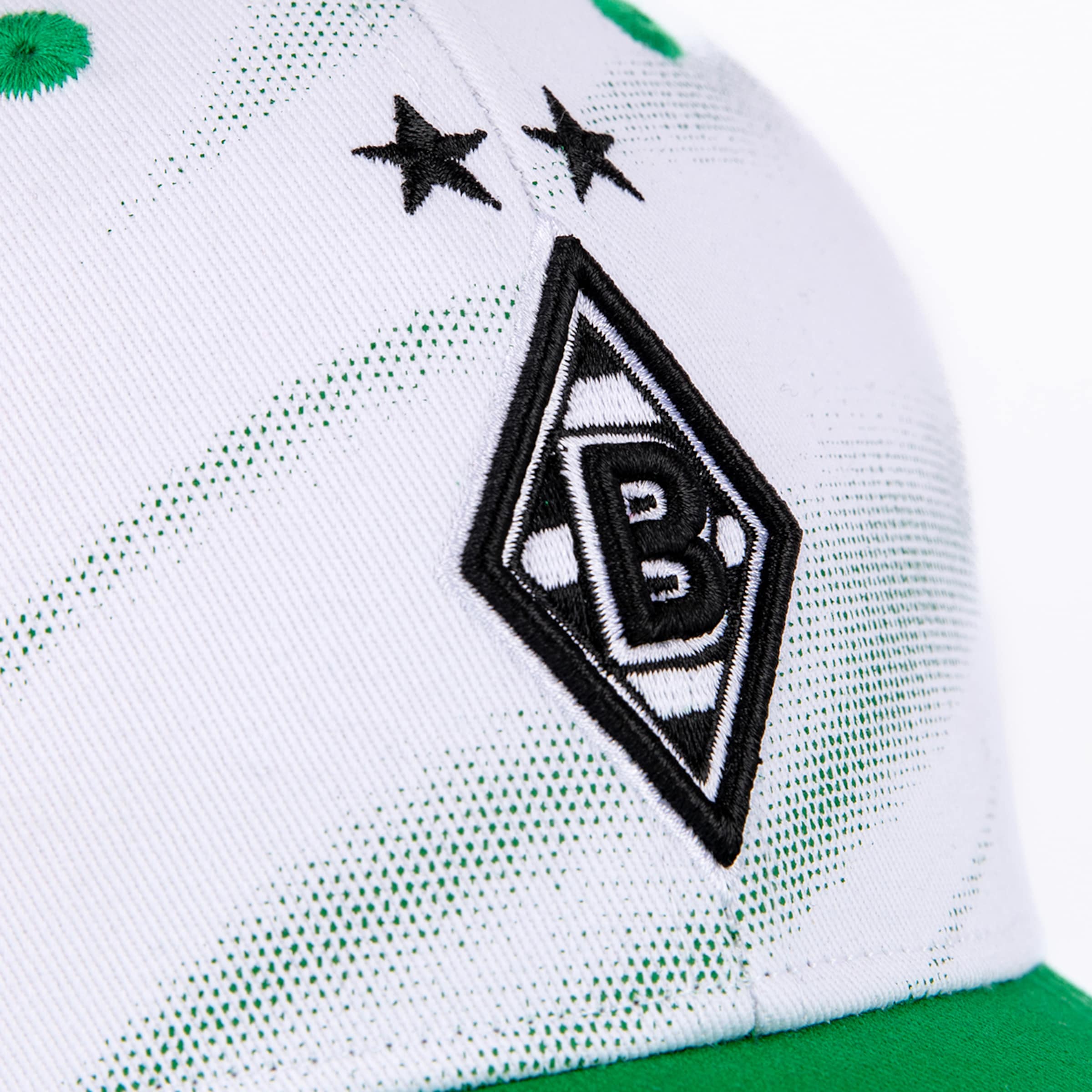 Nahaufnahme einer weißen Kappe mit dem Rauten-Logo von Borussia Mönchengladbach, zwei schwarzen Sternen und grünem Punktmuster.