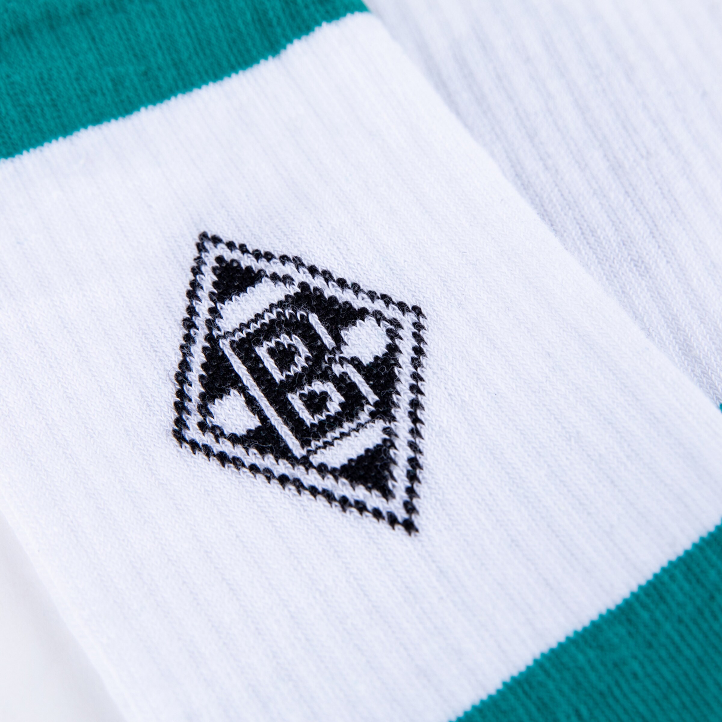 Nahaufnahme einer weißen Socke mit dem schwarzen rautenförmigen Borussia Mönchengladbach Logo zwischen zwei grünen Querstreifen.