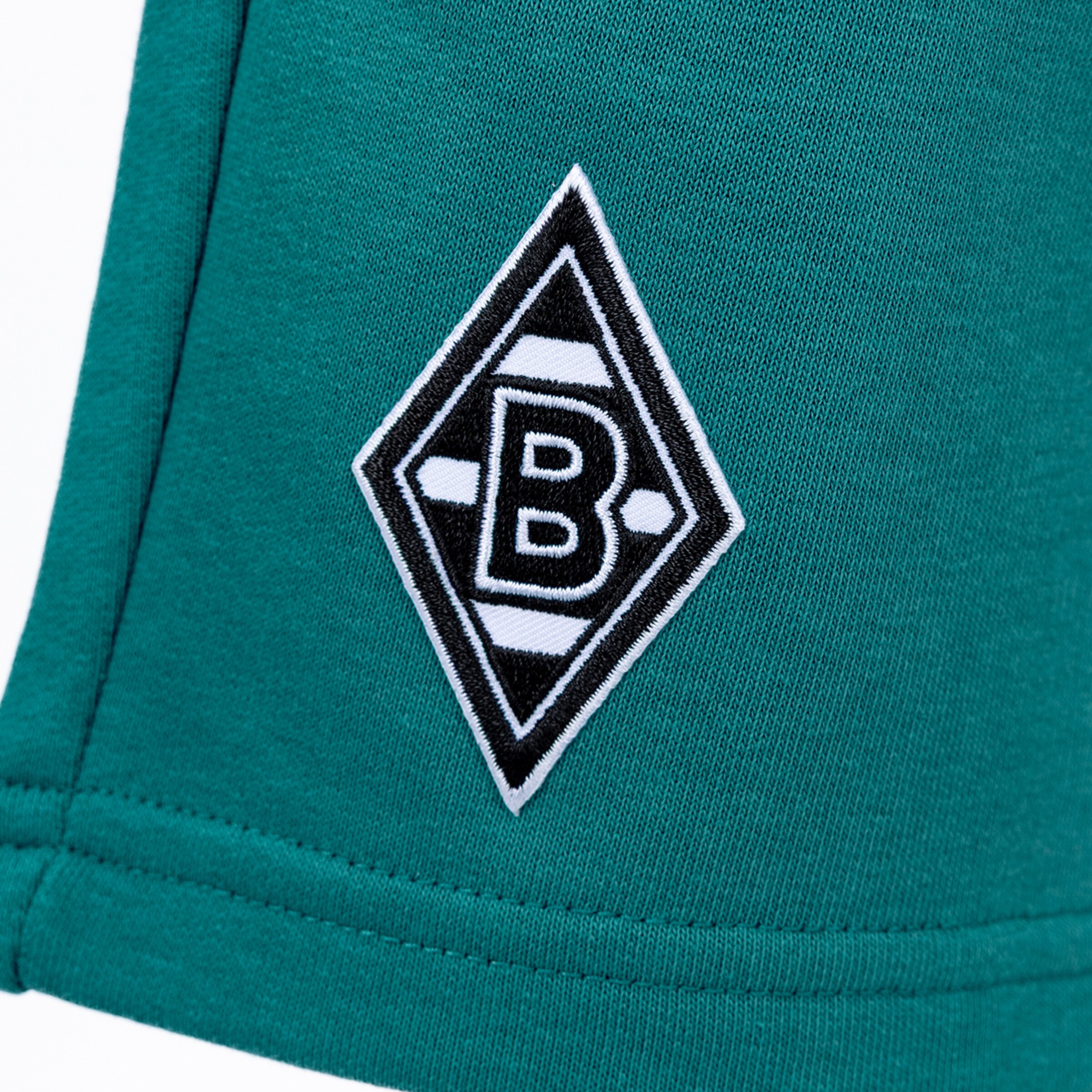 Embroidered Borussia Mönchengladbach logo, a black and white diamond with the letter B, on green fabric.