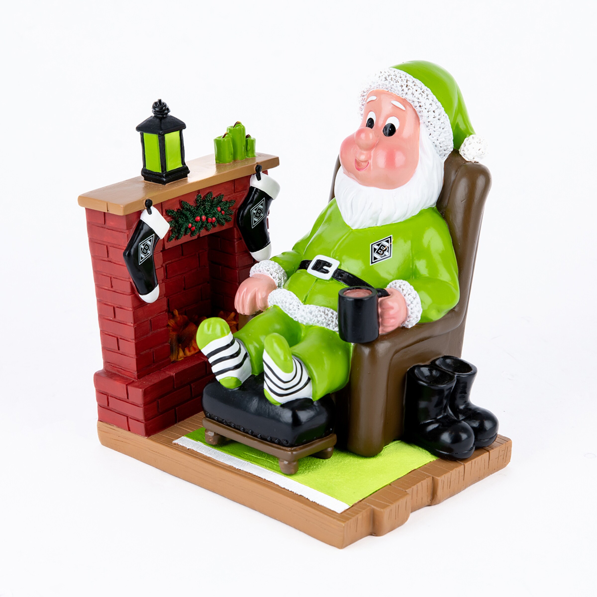 Weihnachtsmann-Figur in grünem Gladbach-Outfit, sitzend im Sessel am Kamin mit Tasse und gestreiften Socken.