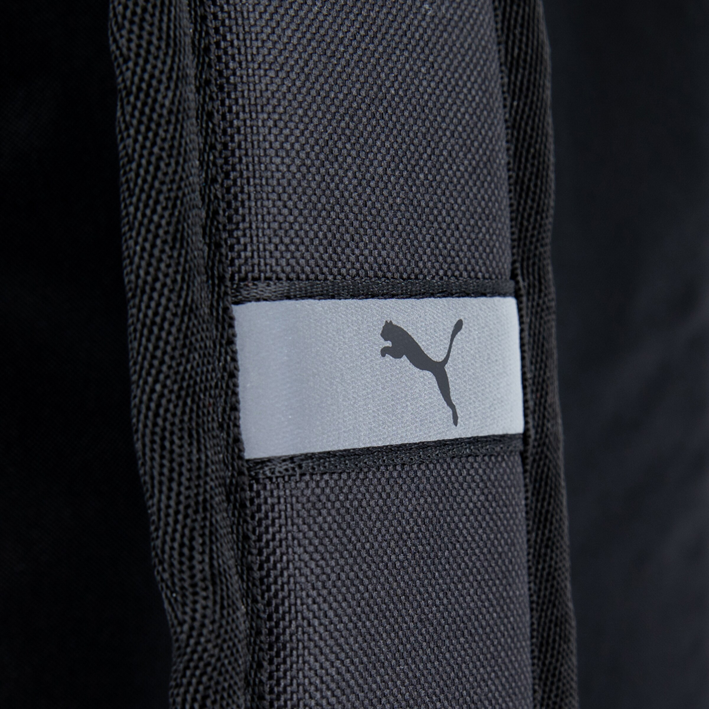 Schwarz-graues Material mit einem Puma-Logo auf einem sportlichen Rucksack.