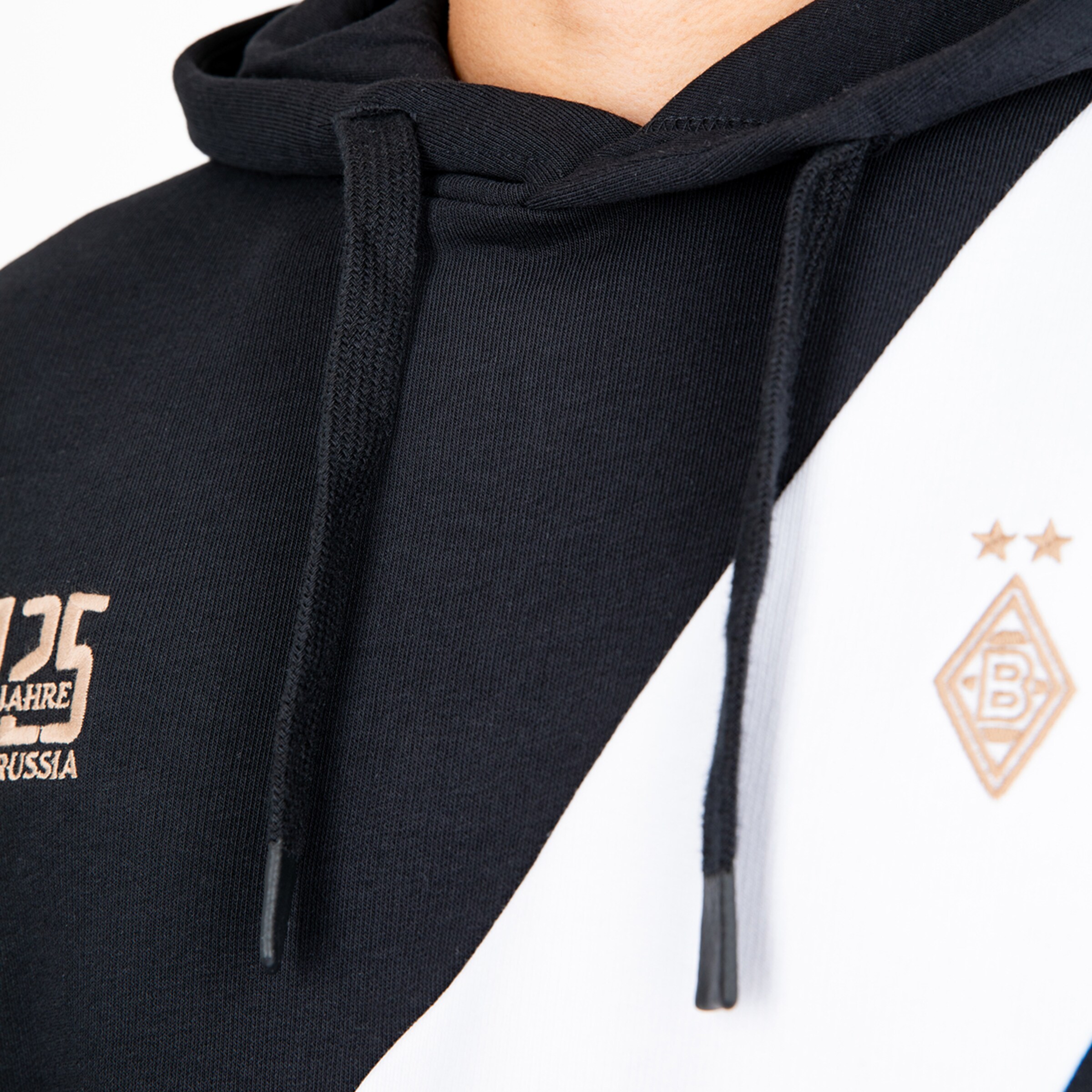 Nahaufnahme eines schwarz-weißen Borussia Mönchengladbach Jubiläums-Hoodies mit goldenem Vereinslogo und „125 JAHRE BORUSSIA“-Schriftzug.