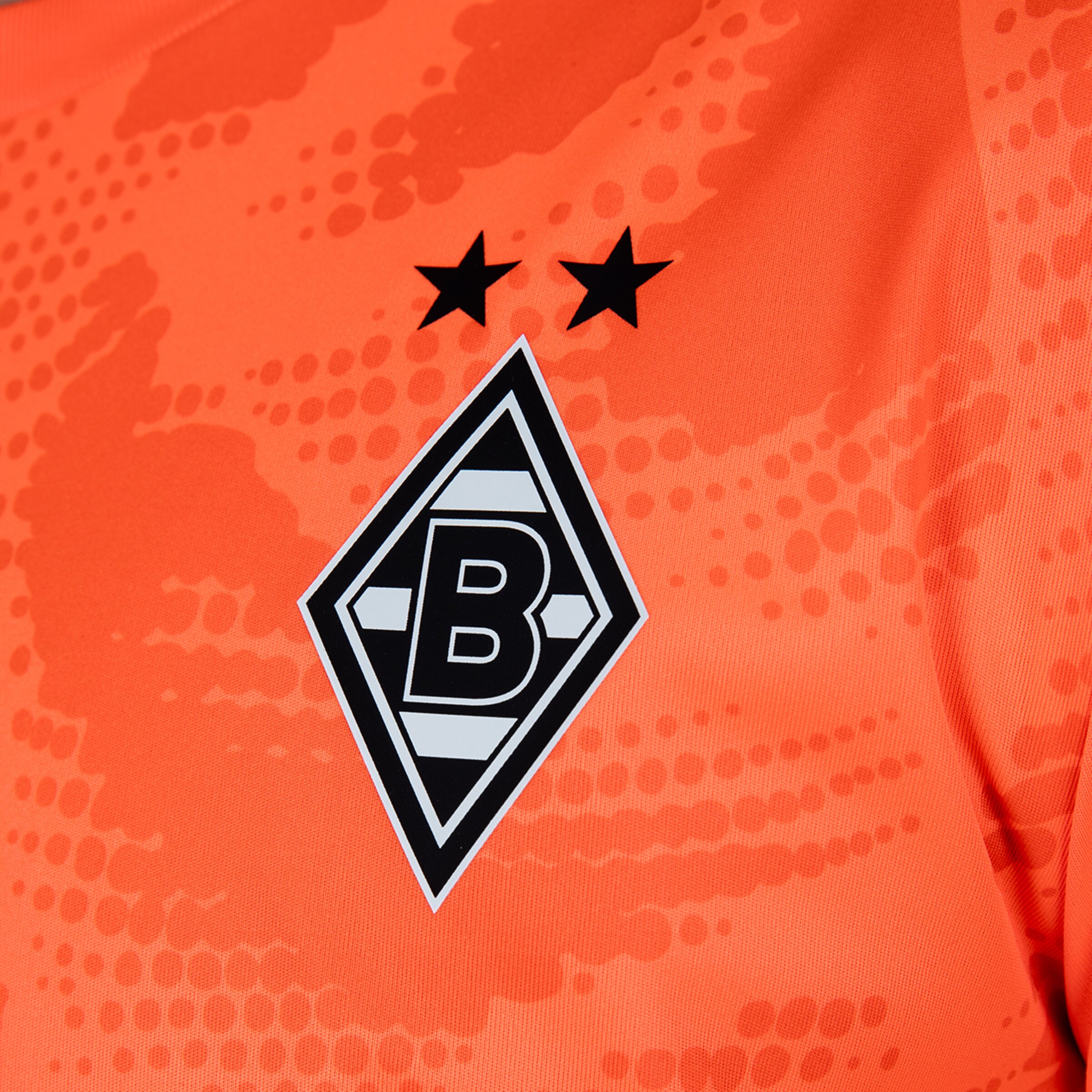 Borussia Mönchengladbach crest on an orange jersey with two black stars above the diamond logo.