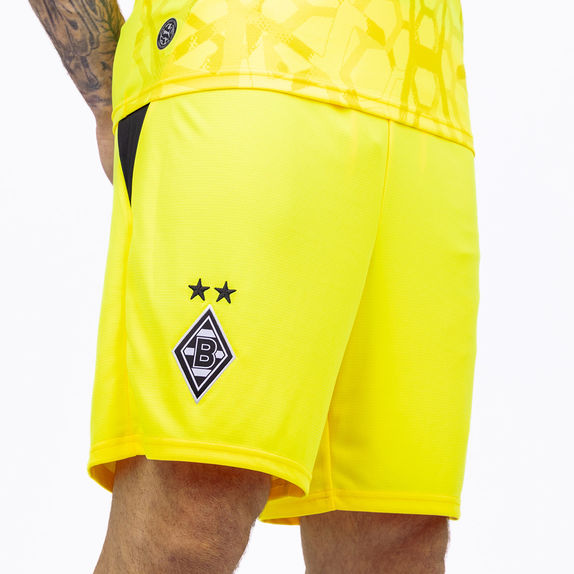 Close-up of yellow football shorts featuring the Borussia Mönchengladbach crest with two stars on the right leg.