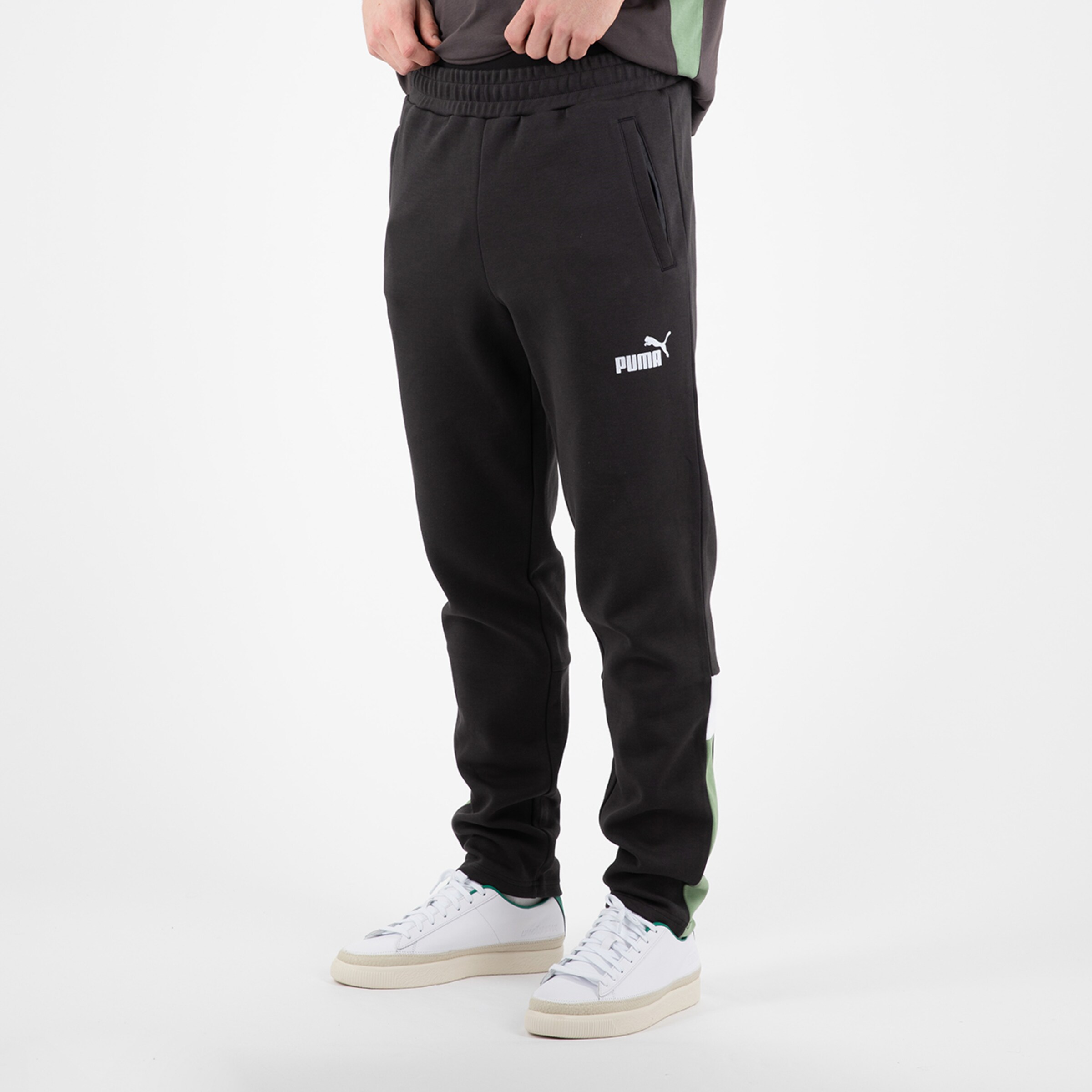 Schwarze Jogginghose von Puma mit grünen Seiteneinsätzen und Taschen.