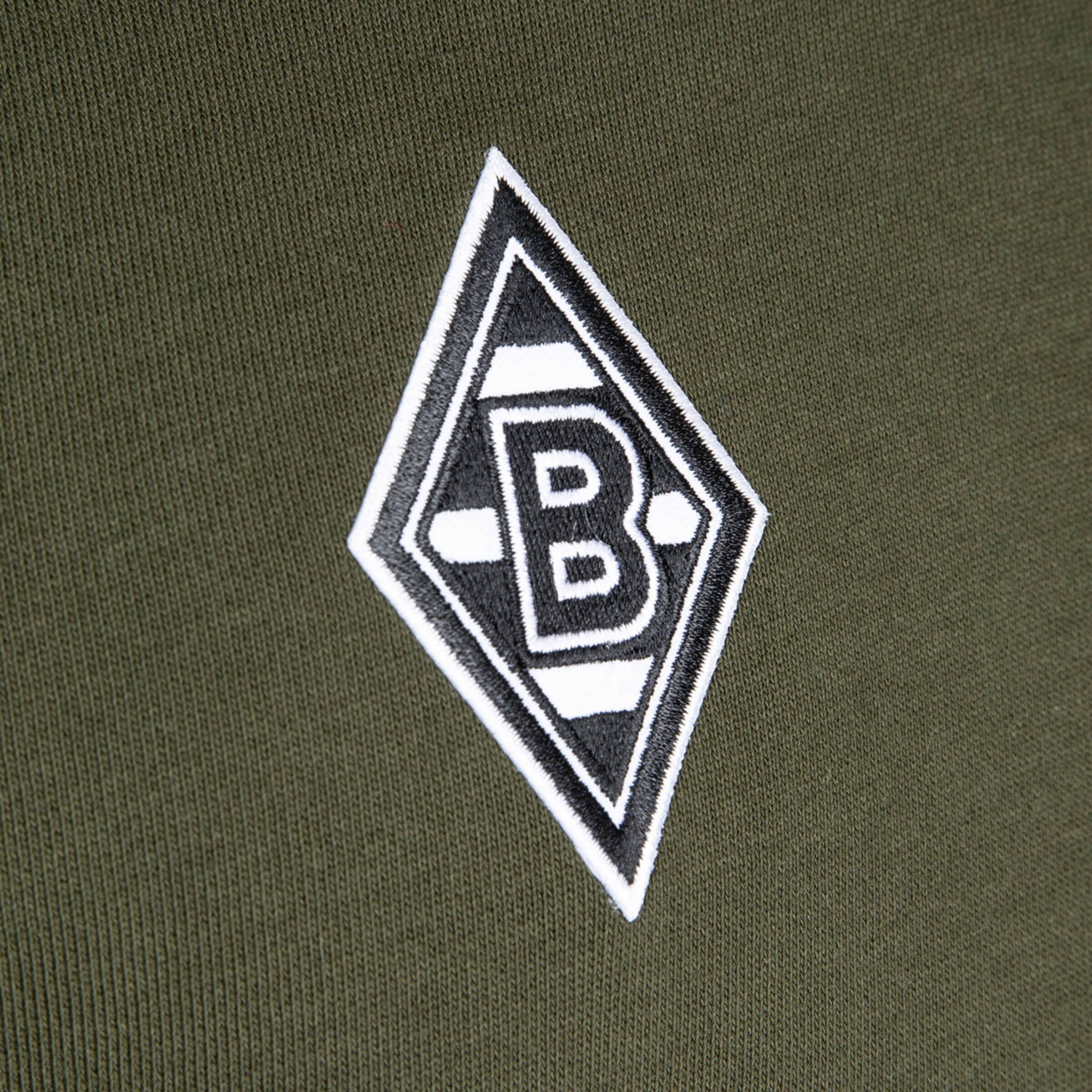 Logo von Borussia Mönchengladbach in weiß und schwarz auf grünem Stoff.