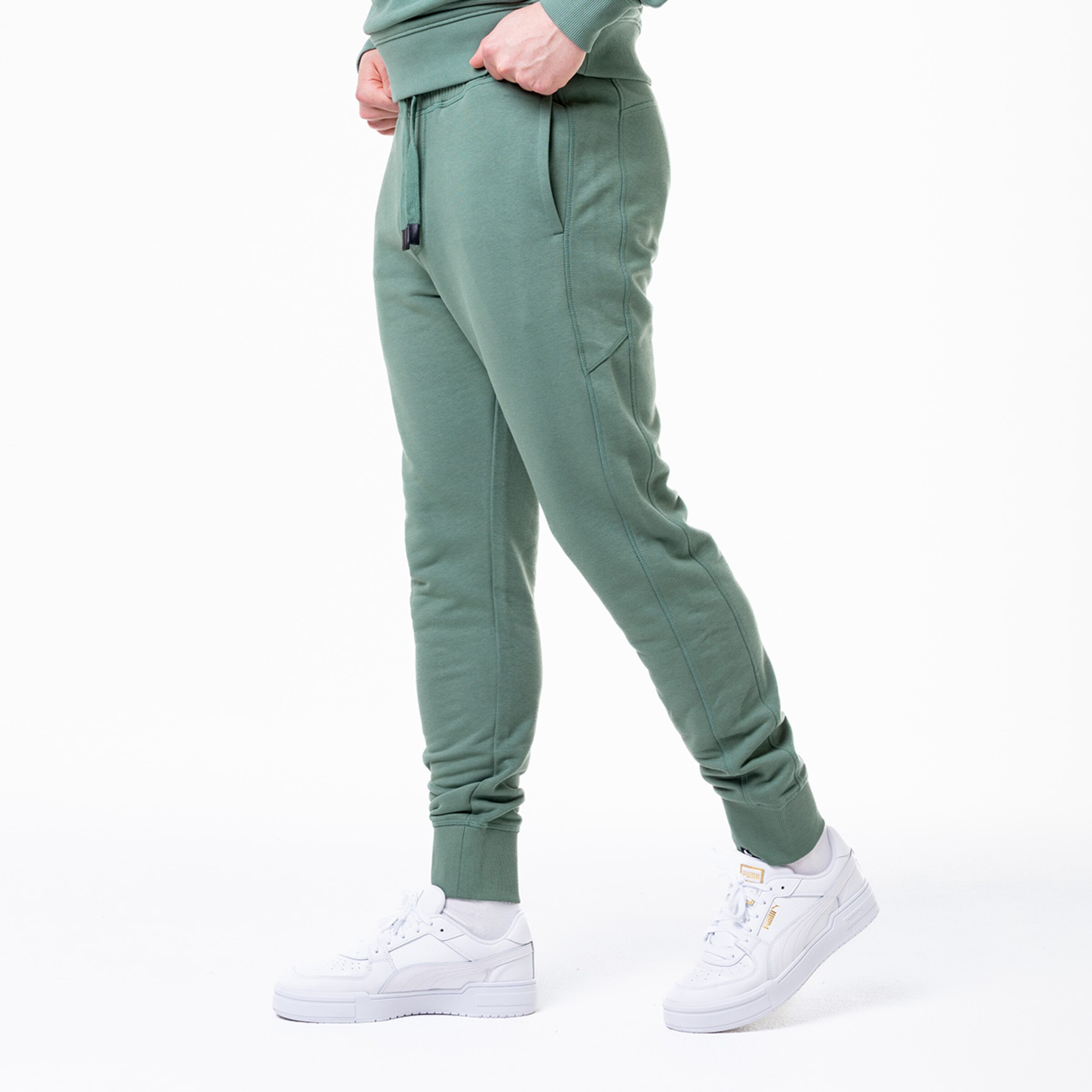Grüne Jogginghose mit Taschen kombiniert mit weißen Sneakers.