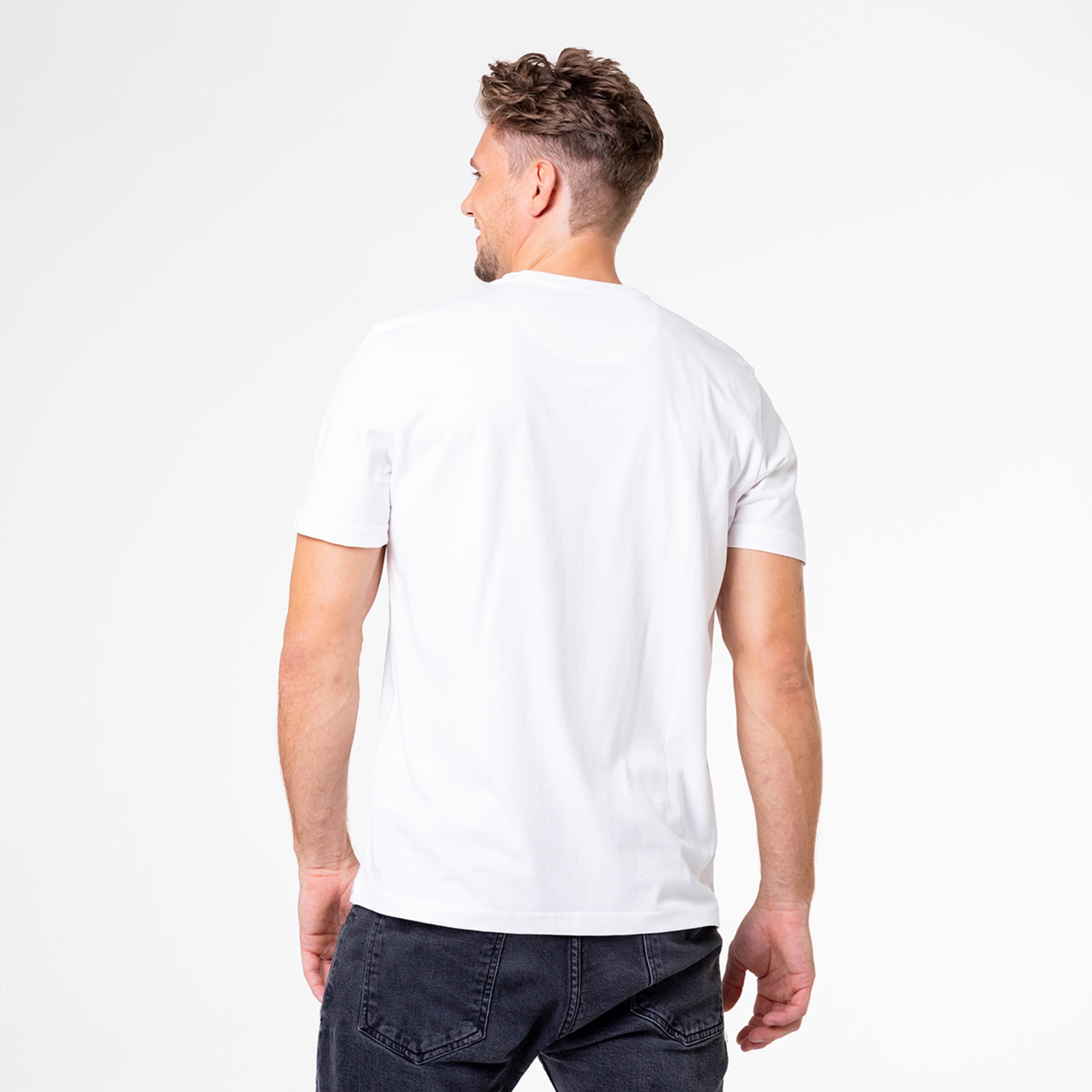 Hinteransicht eines Mannes in einem weißen T-Shirt und dunkler Jeans.