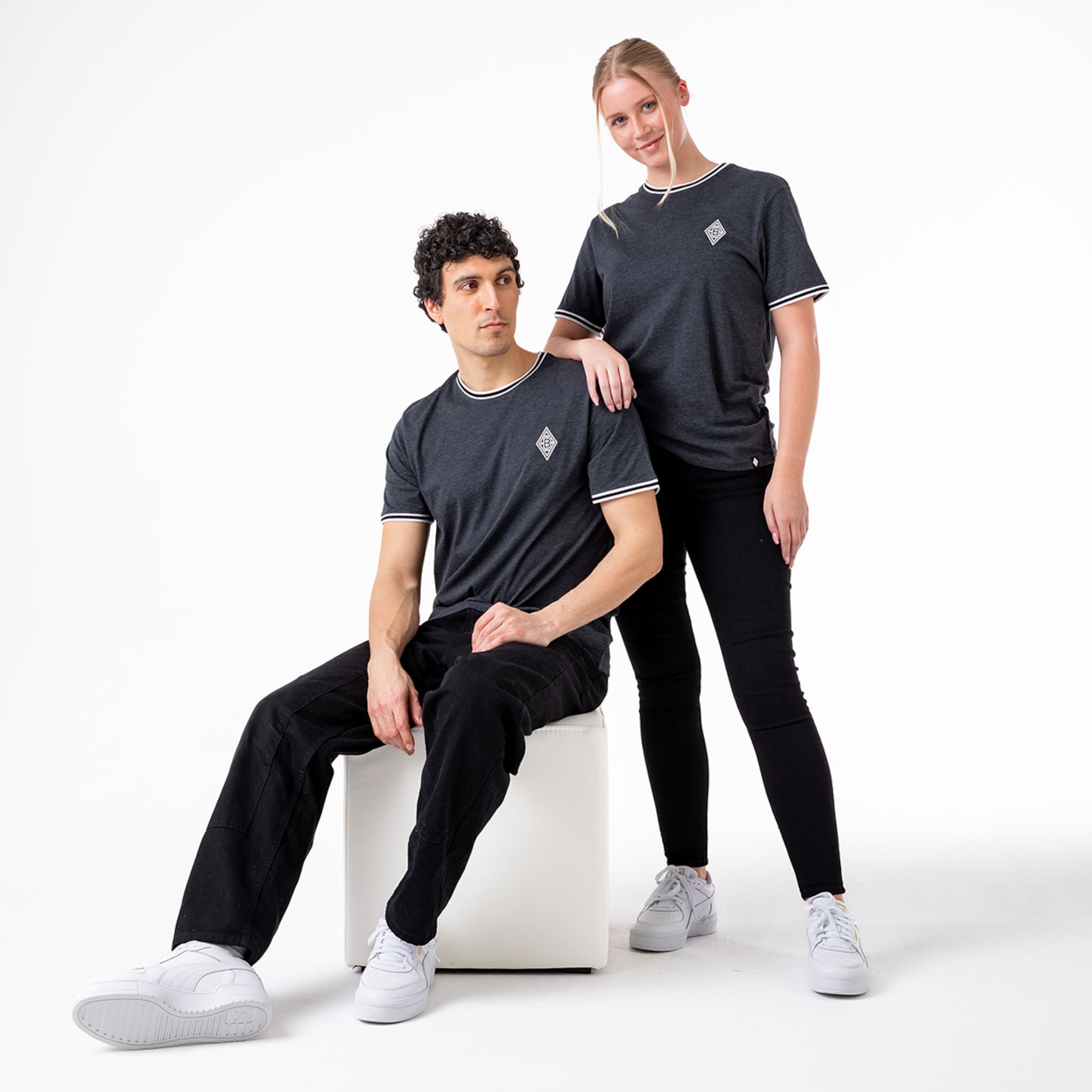 Ein Mann und eine Frau stehen nebeneinander beide in dunkelgrauen T-Shirts mit weißem Kragen und dem Borussia Mönchengladbach-Logo.