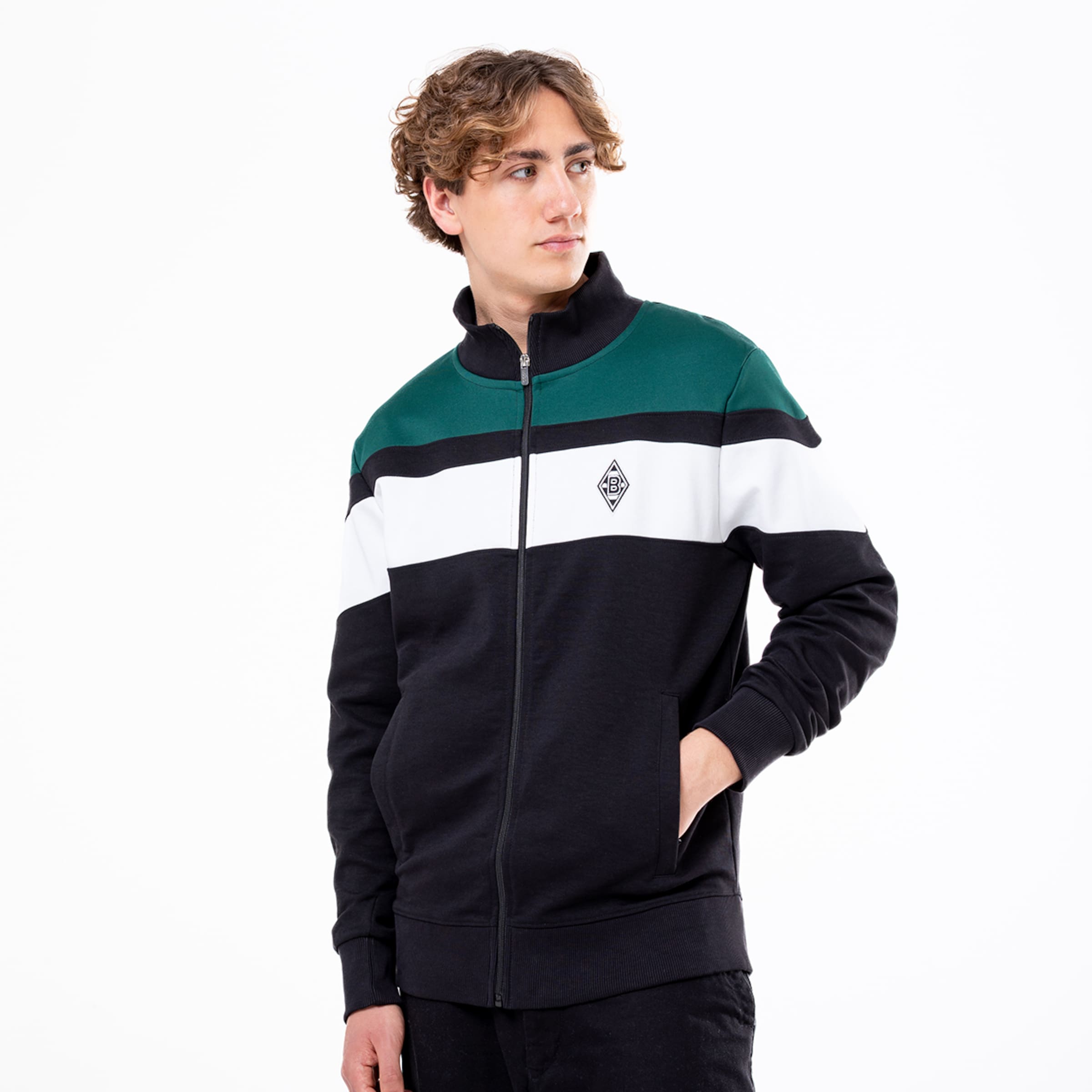 Mann in schwarzer Jacke mit grünem und weißen Streifen trägt eine sportliche Haltung.