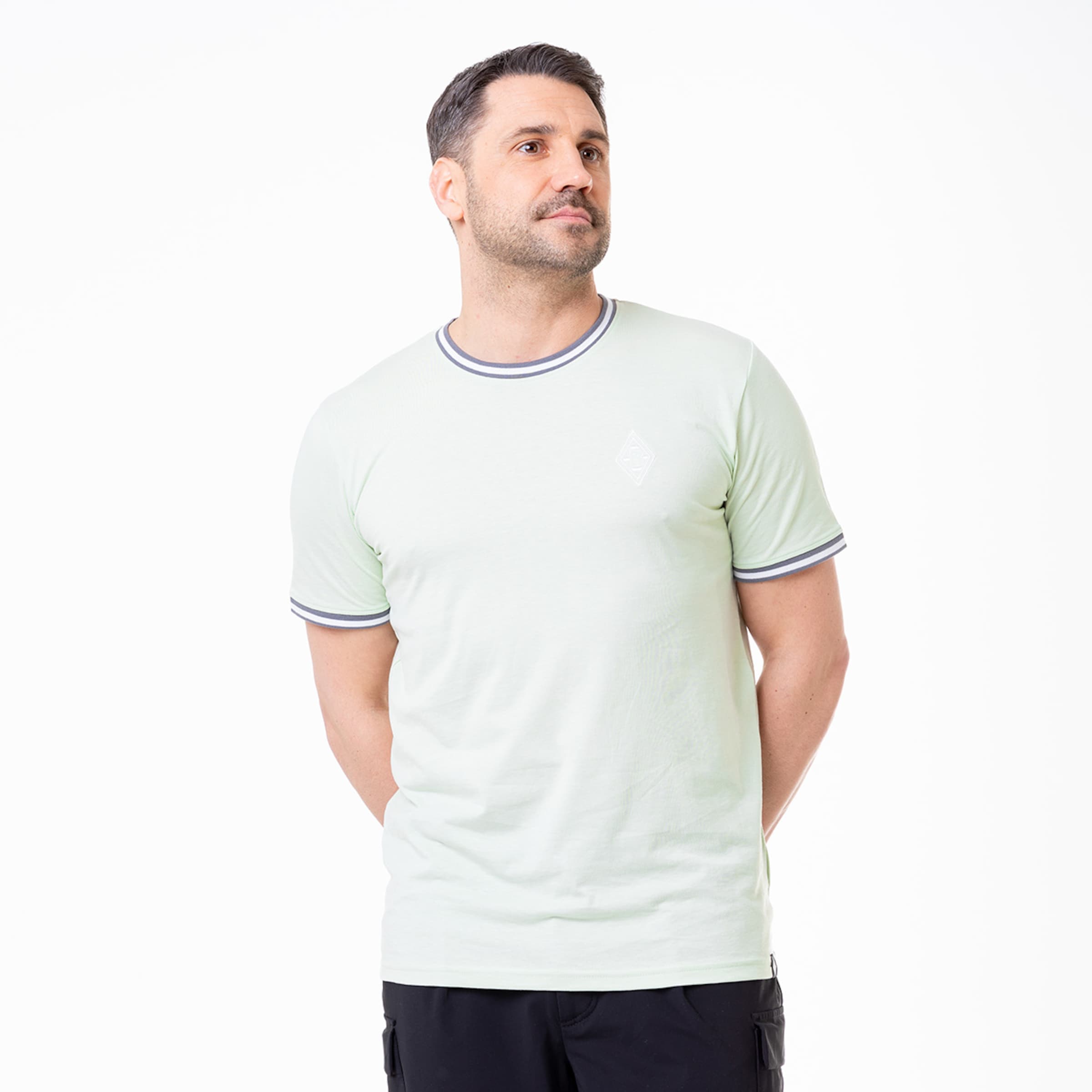 Man standing in a casual light green T-shirt with a round neckline and short sleeves featuring contrasting stripes.