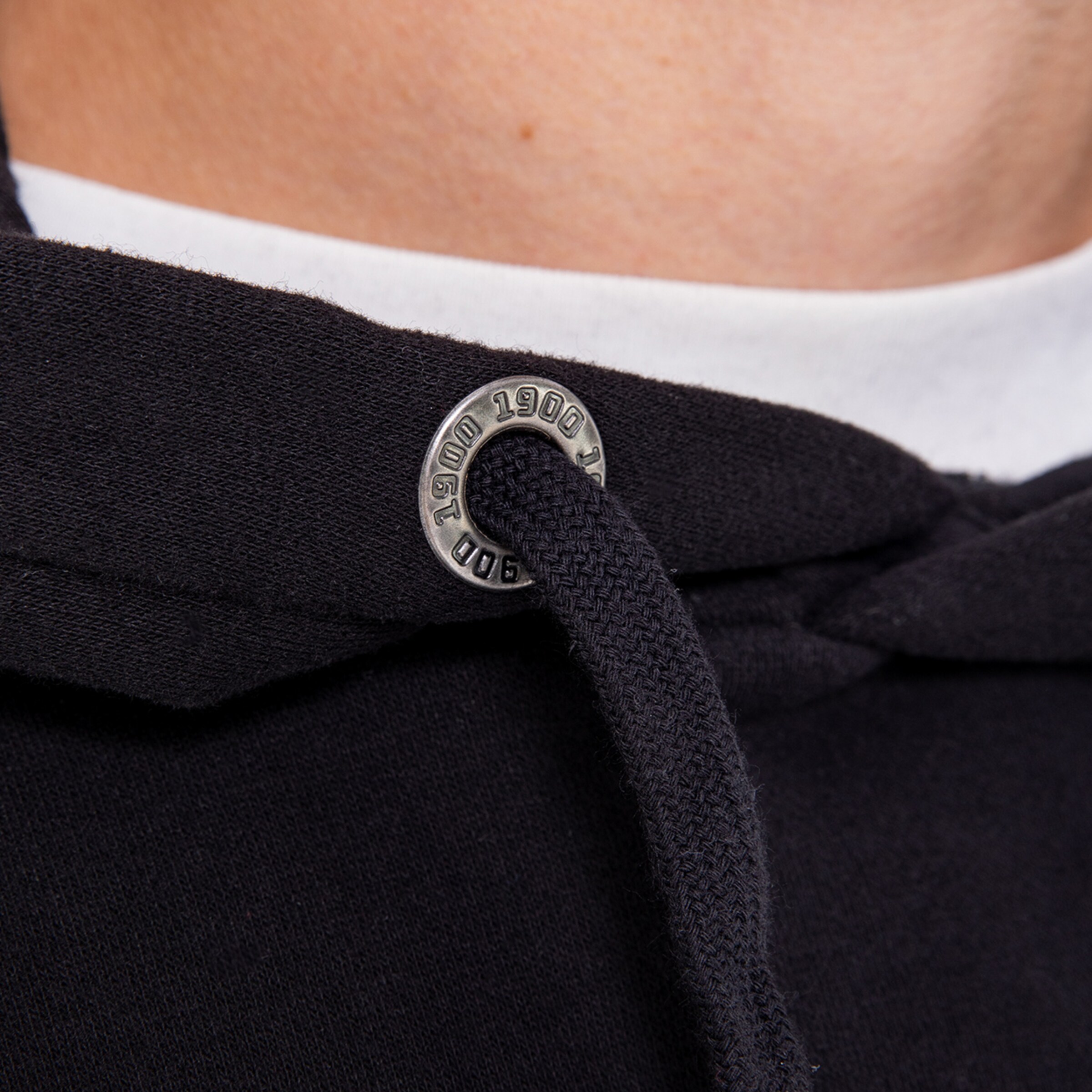 Detailaufnahme einer schwarzen Kapuzenpullover-Schnürung mit Metallösen und Kordel.