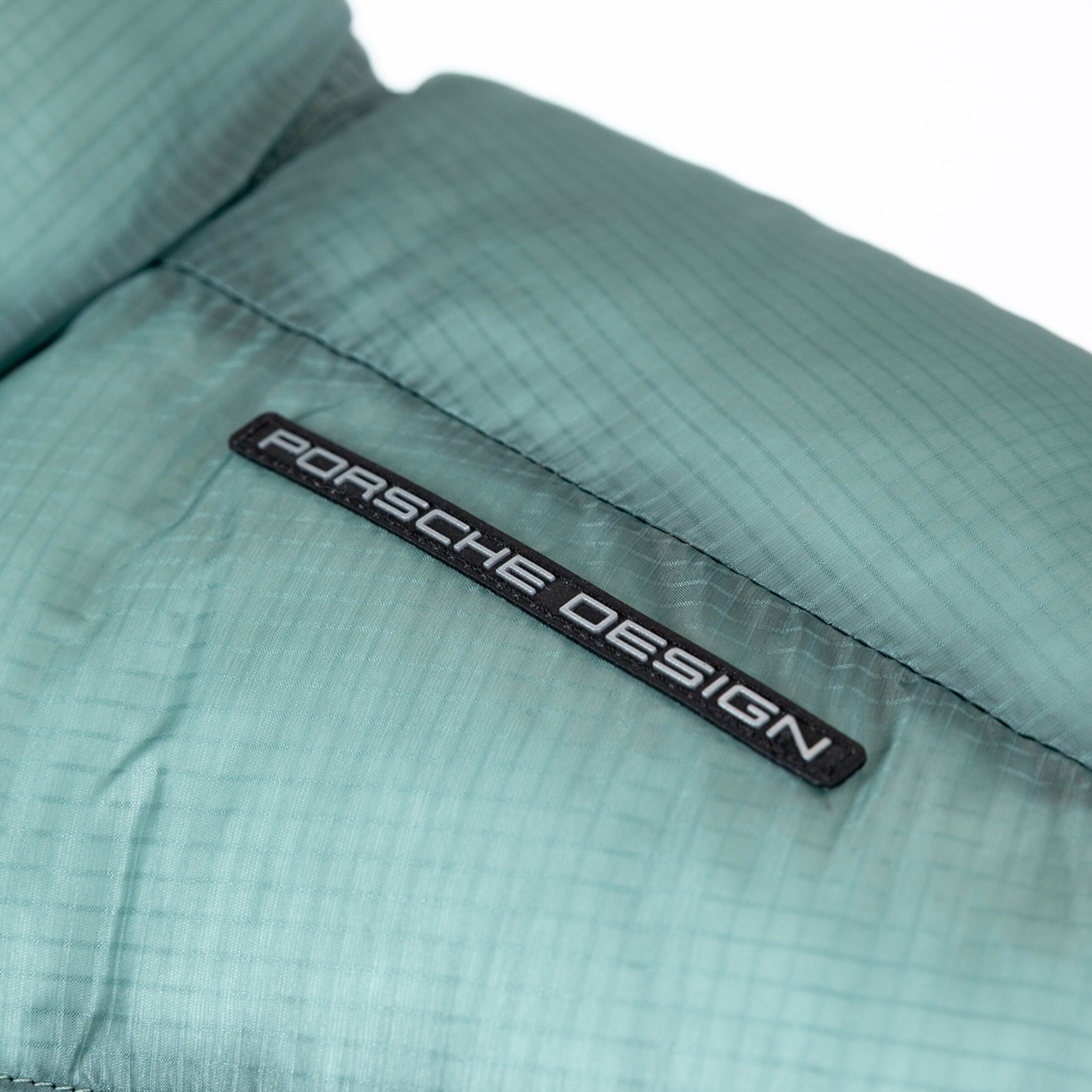 Label mit dem Schriftzug Porsche Design auf einer gepolsterten Stoffoberfläche.