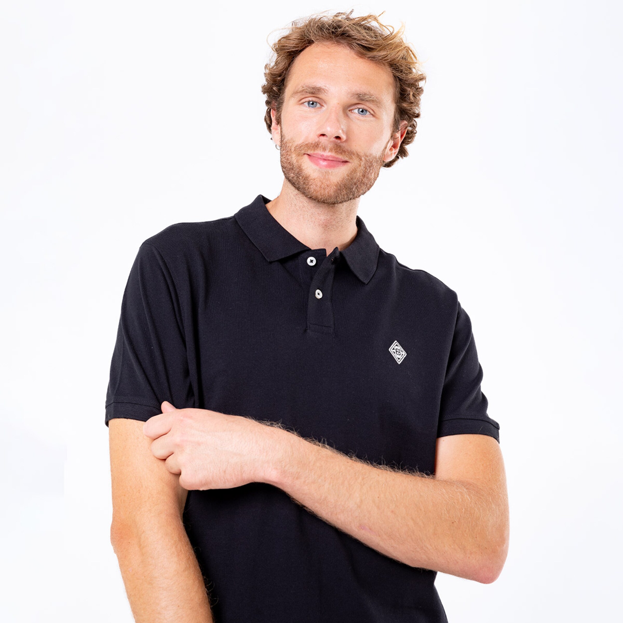 Mann mit kurzem Ärmel trägt ein schwarzes Poloshirt lächelt leicht.