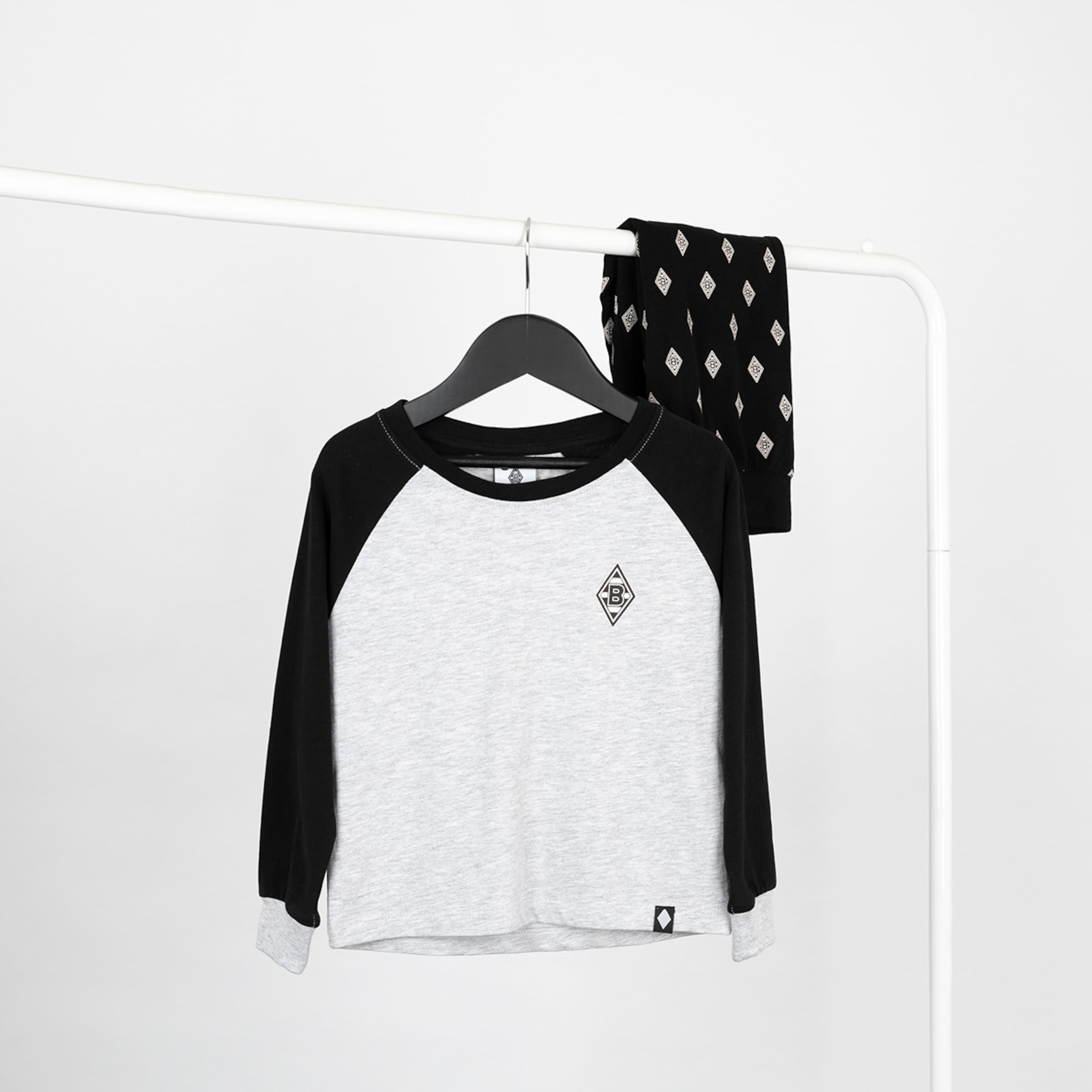 Grau-schwarzes Raglan-Langarmshirt mit Rauten-Logo und passende schwarz gemusterte Schlafanzughose an einer weißen Kleiderstange.