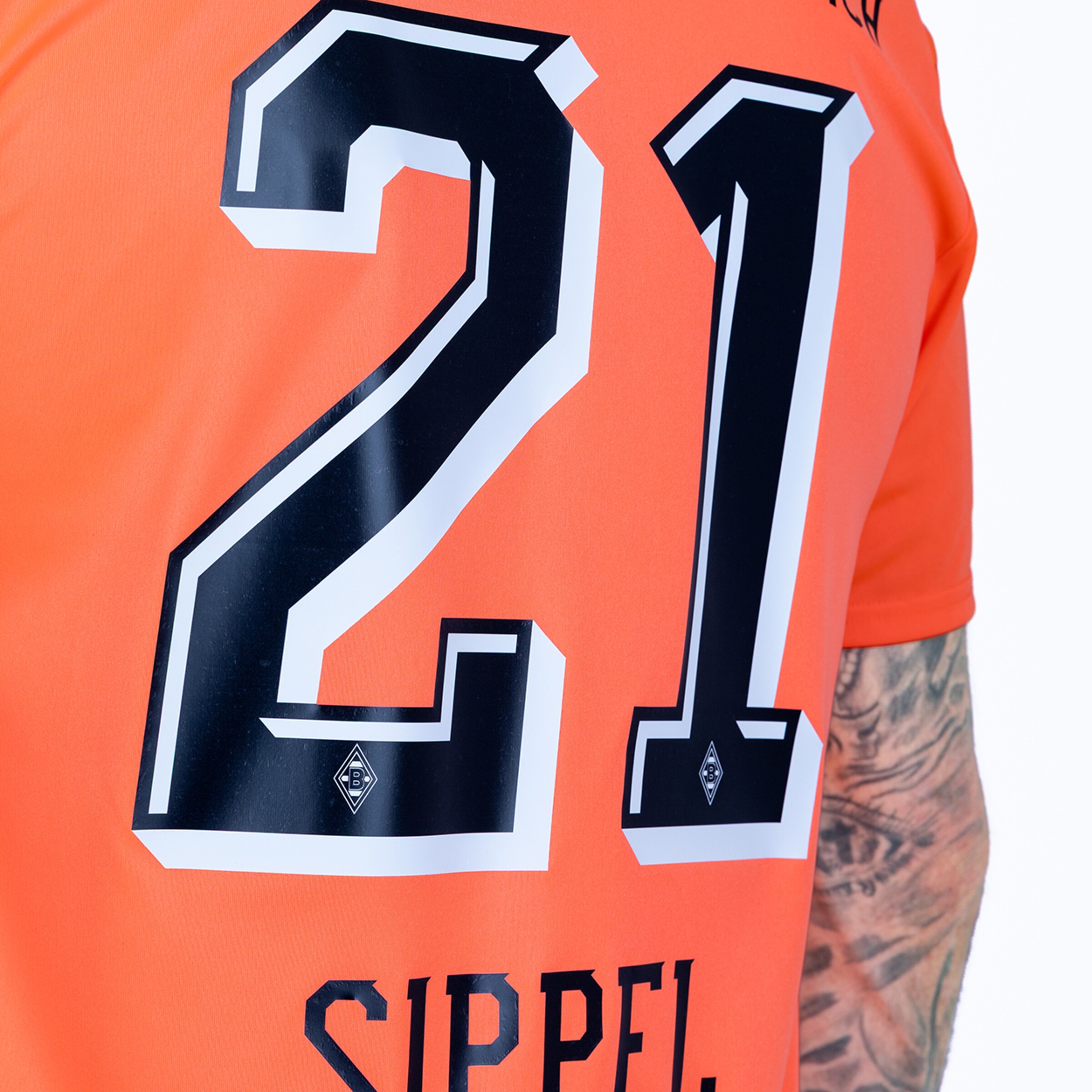 Back view of an orange jersey featuring the number 21 in black and white and the name SIPPEL. A tattooed arm is visible on the right.