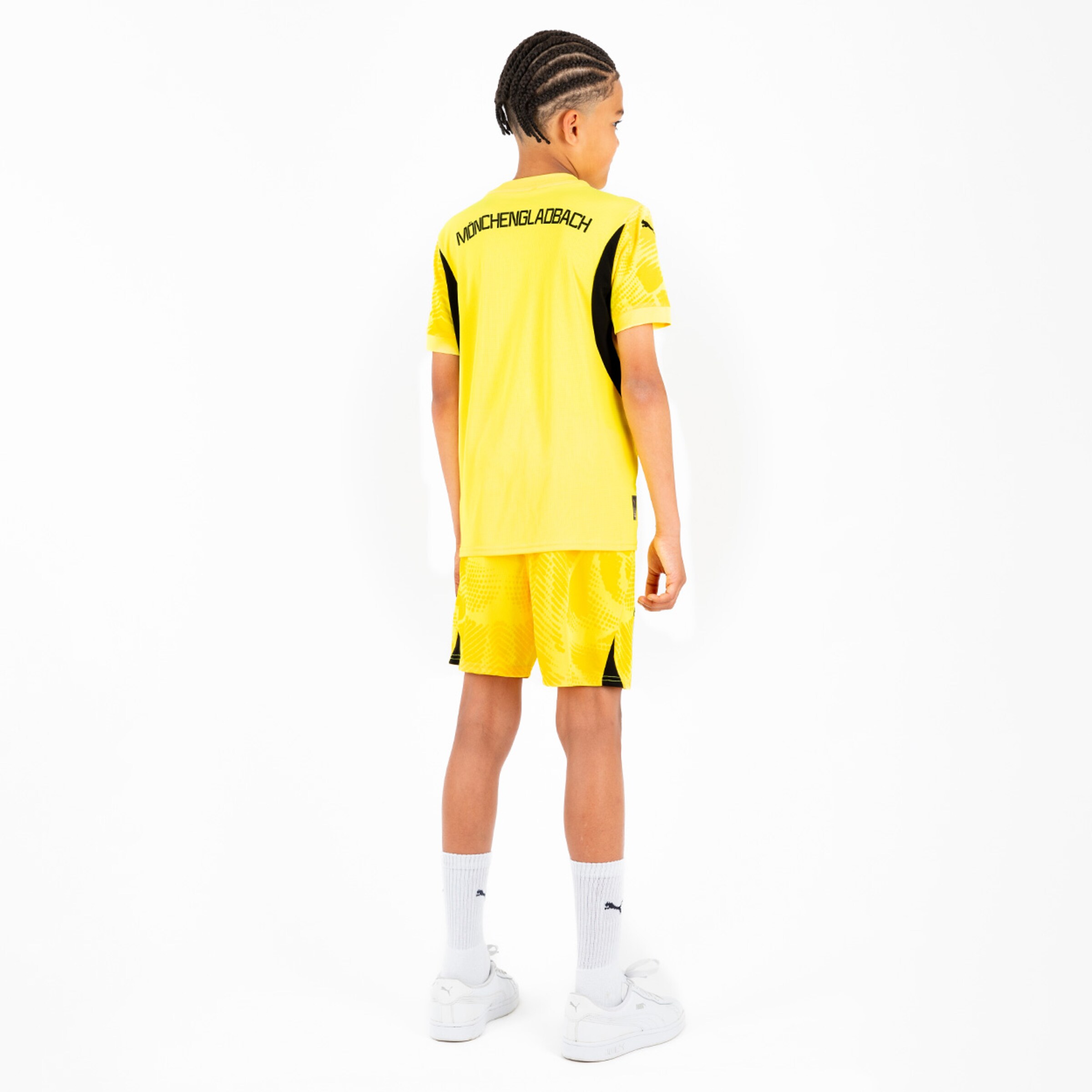 Junge trägt gelbes Borussia Mönchengladbach Trikot und Shorts von hinten.