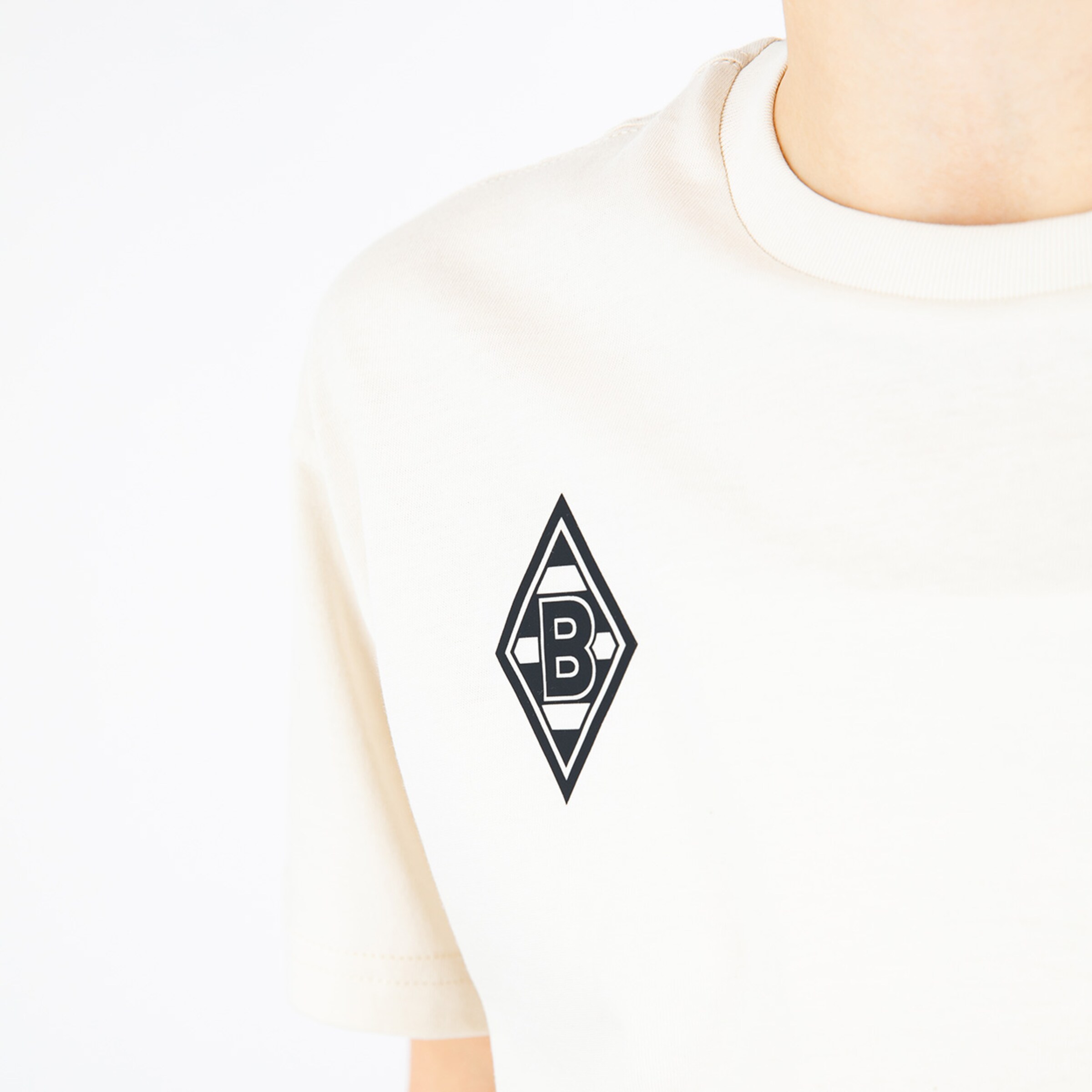 Ein beiges T-Shirt mit dem Borussia Mönchengladbach Logo auf der linken Brust.