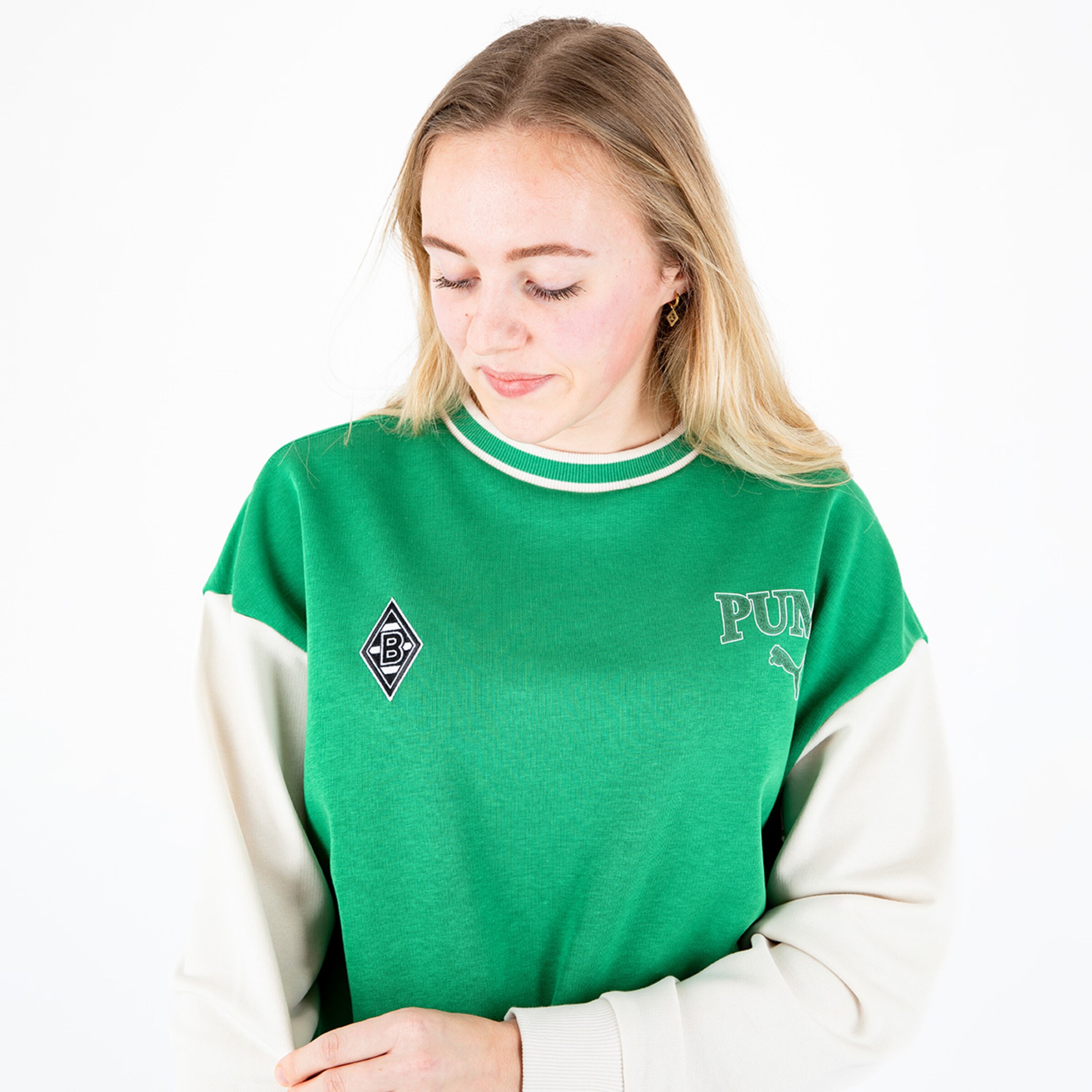 Frau trägt einen grünen Pullover mit weißen Ärmeln und einem Borussia Mönchengladbach Logo.