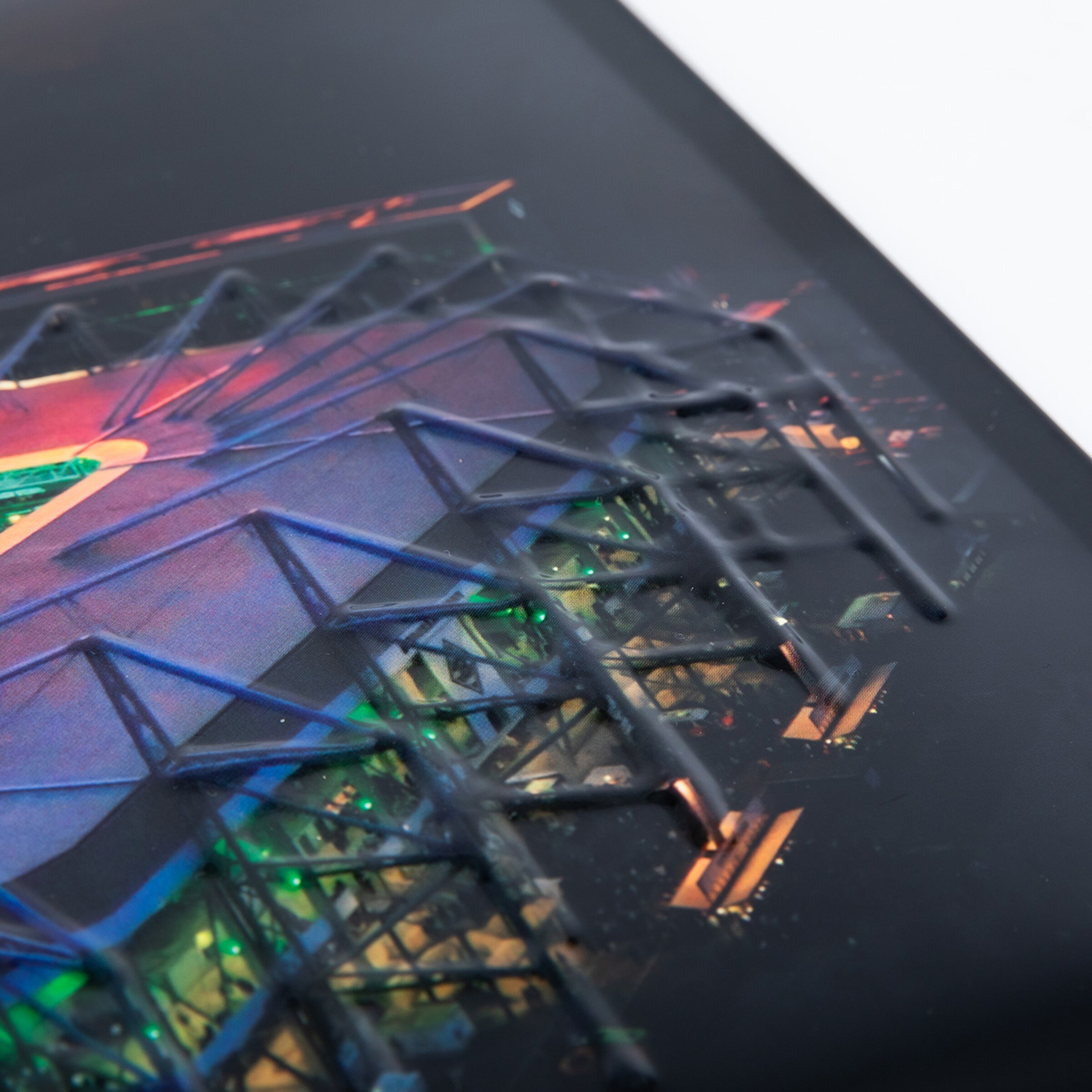 Close-up of a print with 3D varnish. Raised black lines on a colorful architectural motif create a tactile structural grid.