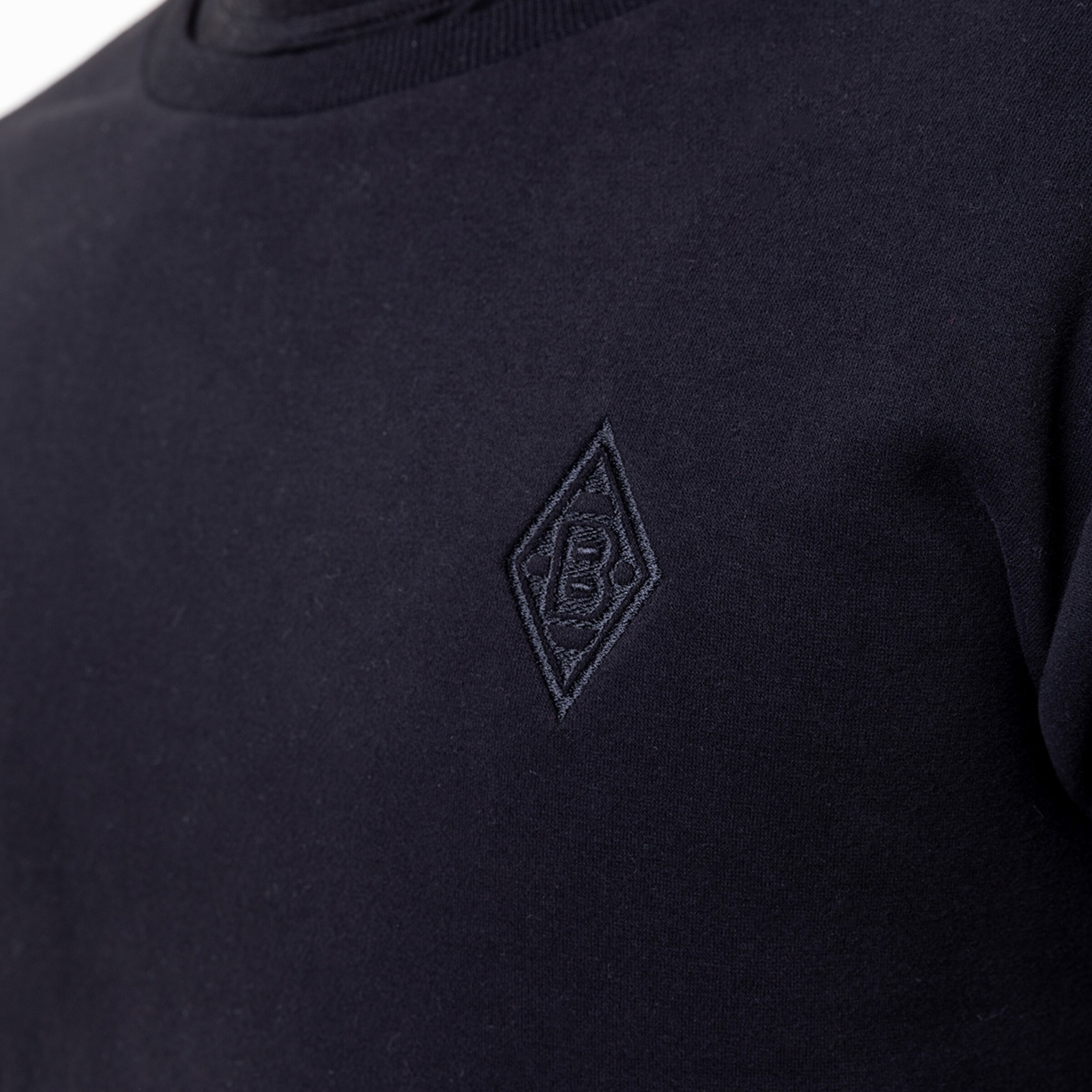 Close-up of a navy sweatshirt featuring an embroidered Borussia Mönchengladbach logo.